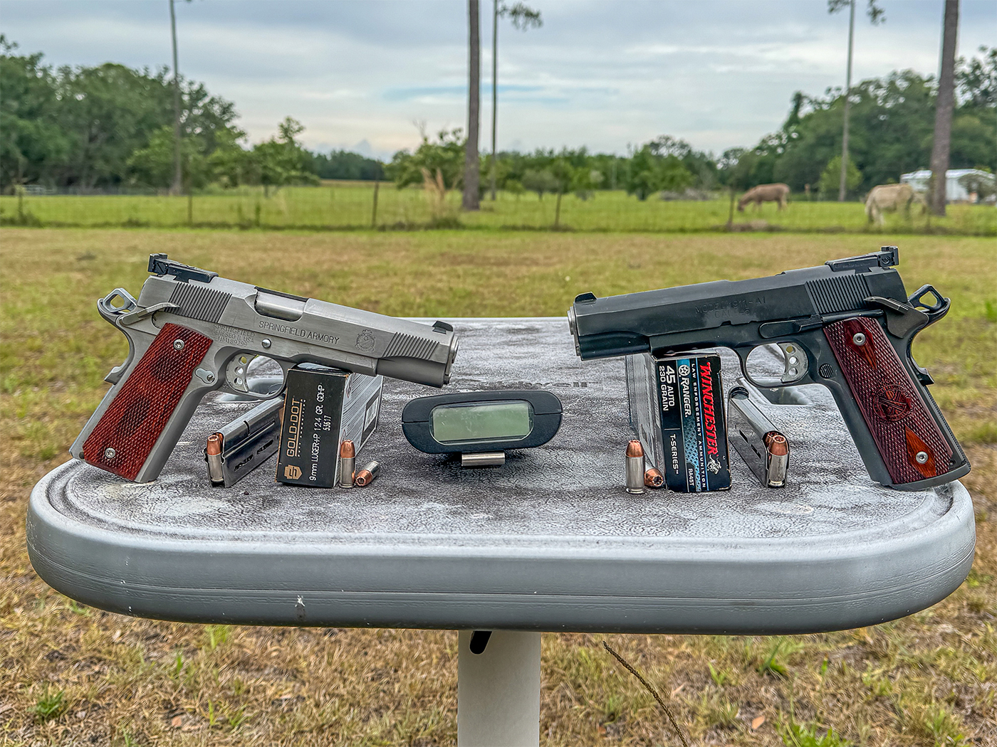 The image shows two 1911 pistols used by Massad Ayoob in his evaluation for the article. One is chambered in 9mm, the other in .45 ACP, both crafted for comparative testing. Displayed together, they reflect on key differences such as recoil and magazine capacity. Ayoob’s choice of these particular models underscores the investigation into caliber effectiveness. The pistols represent a balance of tradition and modern testing in firearm performance. This visual assists readers in understanding the practical testing environment.