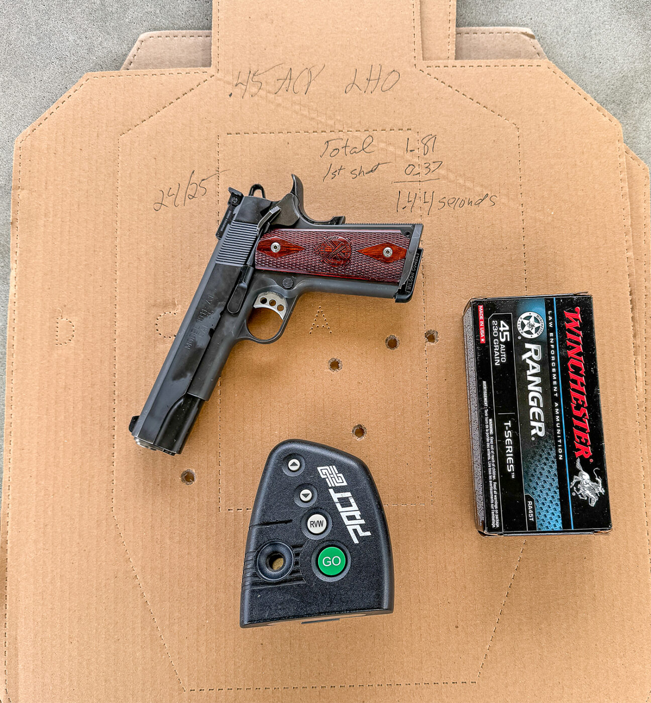 The author's 1911 pistol chambered in .45 ACP is displayed alongside a shooting timer and Winchester Ranger ammunition. The setup reflects the combination of tools used in the comparative testing explored in the article. The .45 ACP ammo is renowned for its stopping power, essential in performance evaluations. The shooting timer indicates precise measurement of speed and efficiency during trials. This image supports understanding the detailed methodology used in the firearm performance investigation.