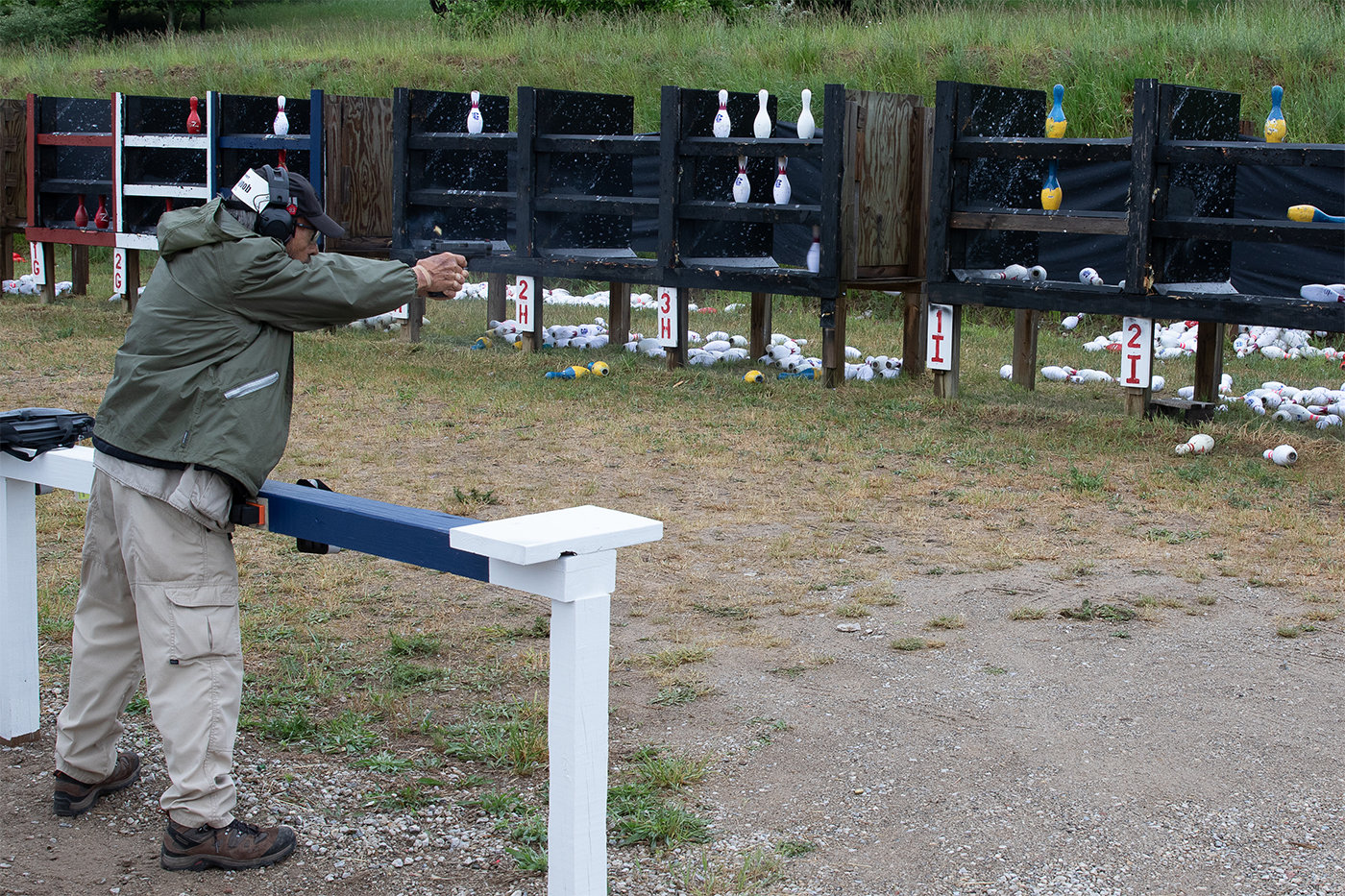 Massad Ayoob is depicted shooting a bowling pin match, utilizing a Springfield Armory XDM Elite. The firearm is known for its ergonomic design and advanced features, making it suitable for competitive shooting. Ayoob's stance and focus highlight his expertise in handling firearms during high-pressure scenarios. The match setting provides a practical environment for testing performance and accuracy. This scene exemplifies a real-world application of firearm skills and equipment. It supports discussions on caliber effectiveness and shooting speed comparison.