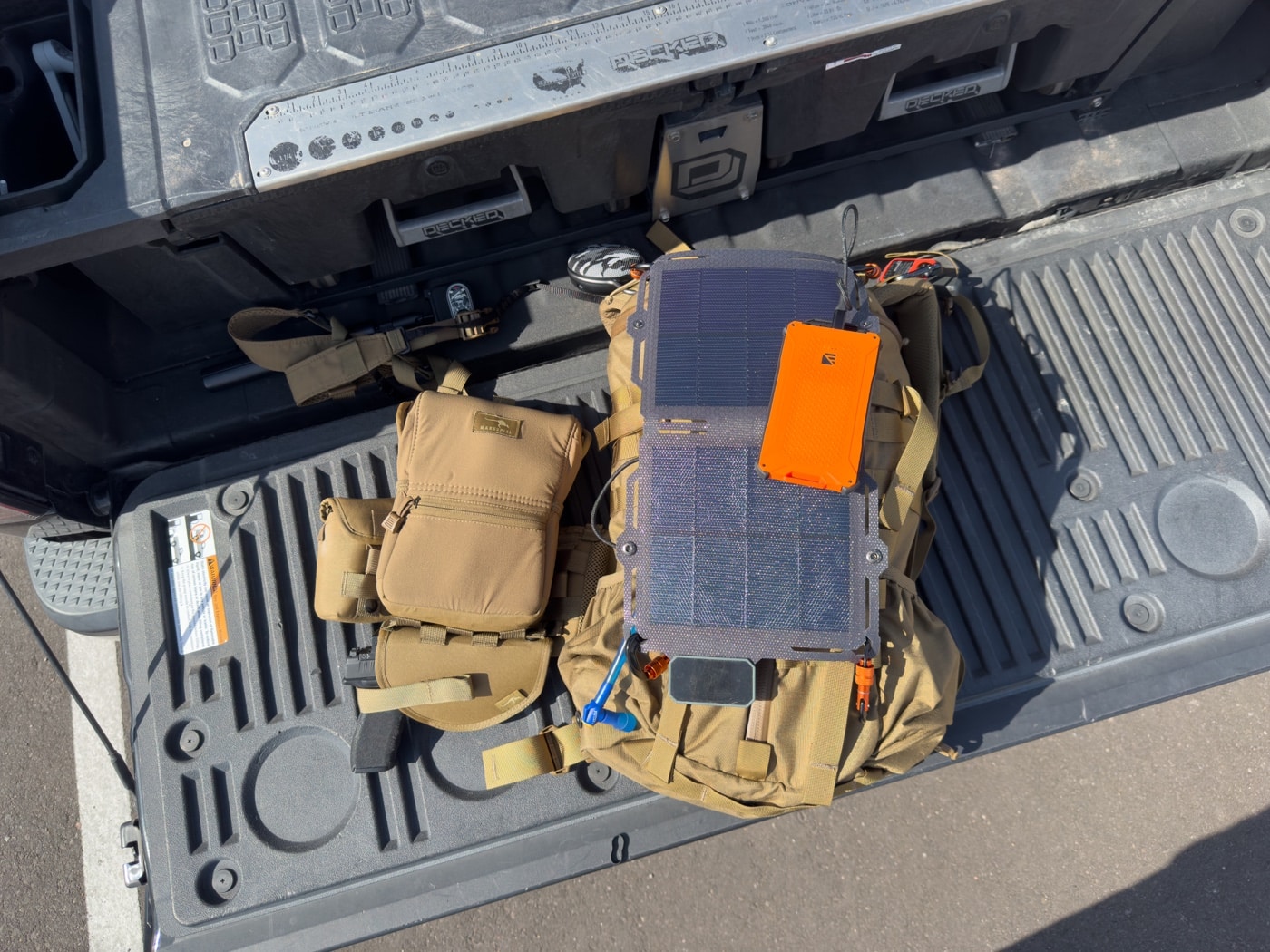 Dark Energy review captures the Spectre 8W solar panel lashed to a backpack during a daytime hike. The panel’s slim, flexible design conforms to pack shape while collecting solar power. You can see the braided paracord cable plugged into the charging port leading to a battery inside. It’s an ultralight solar charger that keeps your electronics topped off on the go in this Dark Energy review. This image illustrates real-world off-grid power harvesting while moving.
