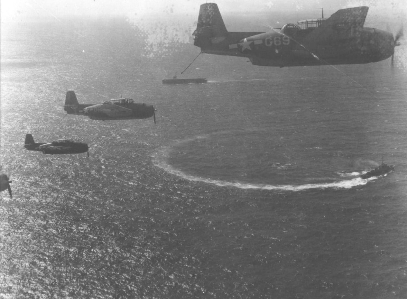 Grumman TBF Avengers in flight over ships in the Pacific Ocean