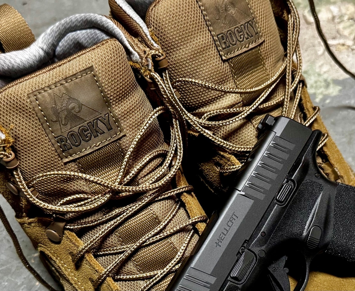 Tight shot of the Rocky Mountain Combat Boot tongue area displaying a woven Rocky logo tag. The tag reads “Rocky” in white letters on a black background with stitching visible along the edges. Surrounding the tag, the coyote tan leather and nylon tongue material meet, showing neat seam placement. Light shadowing around the collar accentuates depth and texture. This detail image reinforces the Rocky Mountain Combat Boot Review by spotlighting brand heritage and craftsmanship.