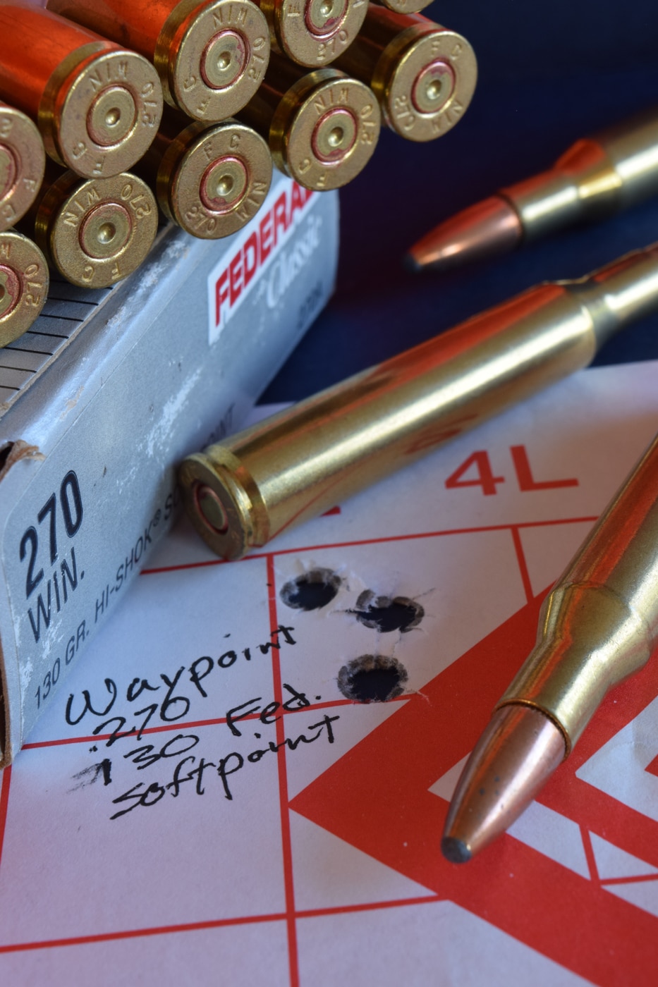 A paper target shows three bullet holes clustered inside the center ring. The perforations lie within a half-minute-of-angle group at 100 yards, demonstrating factory-load precision. Grid lines etched into the paper help gauge the exact group size for downrange accuracy analysis. This tight string of shots highlights the .270 Winchester’s flat trajectory and high muzzle velocity. Uniform hole edges indicate stable bullet impact and effective sectional density of the 130-grain load. Concentric scoring rings and hash marks offer context for ballistic performance evaluation. The tight bullet grouping underscores reliable factory ammo consistency without custom handloads. The image illustrates the .270 Winchester’s reputation for precision shooting and medium-game hunting.
