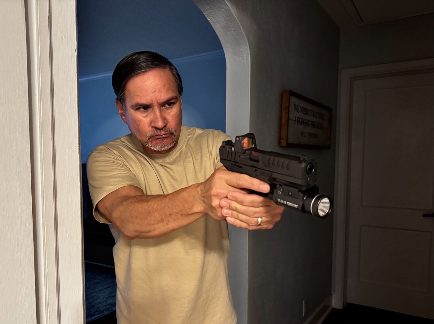 The author is holding a Springfield Armory Echelon handgun in a ready but safe position as he checks out a noise or disturbance inside his home. This image represents how homeowners might respond to unexpected sounds at night or during times when a break-in or home invasion could occur. The author maintains awareness of his surroundings, displaying responsible trigger discipline and keeping the firearm pointed in a safe direction. Approaching unknown situations with care, while prepared to defend oneself, is a critical part of how to survive a home invasion. This scenario reinforces the importance of training, knowing your home’s layout, and having a plan for investigating suspicious activity. Proper firearm handling and a cautious approach reduce the risks to yourself and others if you think there might be an intruder. Checking a disturbance reminds readers to combine vigilance, safety, and readiness in home defense situations.