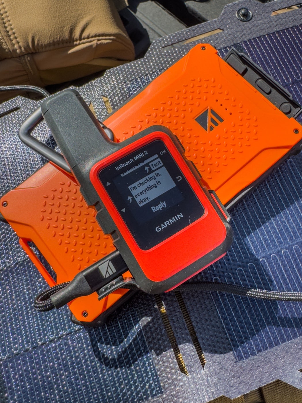 Dark Energy review shows the Spectre solar panel directly charging a Garmin InReach Mini satellite communicator via USB connection. The device sits atop a rock with the cable plugged into the panel’s hub. The bright sunlight and panel positioning indicate effective solar harvesting. It’s an off-grid power method for critical communication gear in this Dark Energy review. The photo illustrates direct charging of electronics in remote locations.