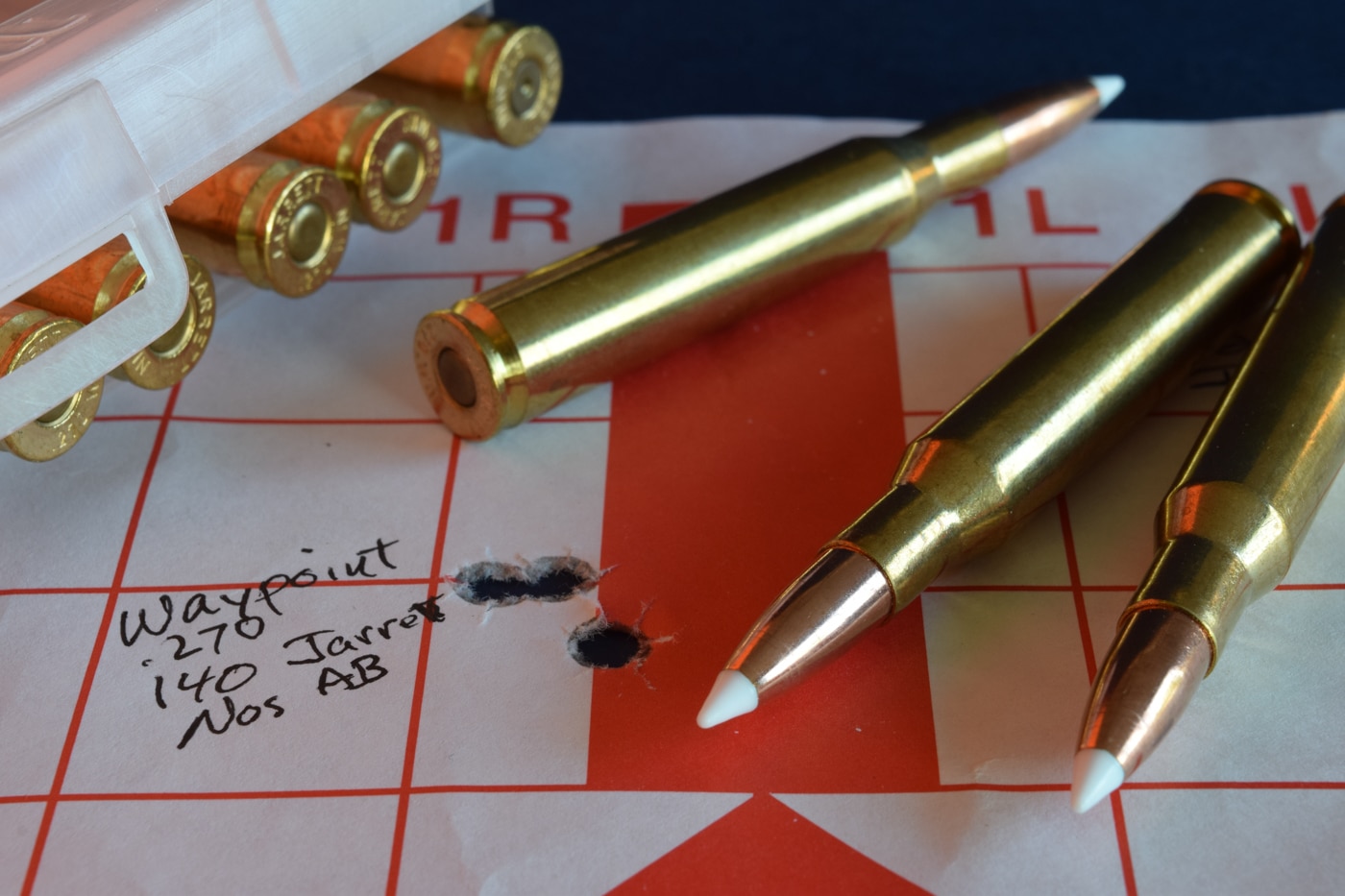 Close-up of a white paper target at 100 yards showing five .270 Winchester factory-load holes clustered inside the bullseye. The tight pattern measures well under half-minute of angle, demonstrating consistent shot placement. Faint grid lines printed on the paper help gauge the extreme precision of each impact. These factory .270 loads fired from the Springfield Waypoint drilled sub-MOA groups without any handloading. Crisp hole edges and uniform spacing reveal the cartridge’s stable muzzle velocity and high ballistic coefficient. This image underscores the Waypoint rifle’s ability to harness the .270 Winchester’s flat trajectory and inherent accuracy. It highlights the reliability of modern factory ammunition in delivering match-grade group sizes. The result speaks to the .270’s reputation for downrange energy and pinpoint precision.
