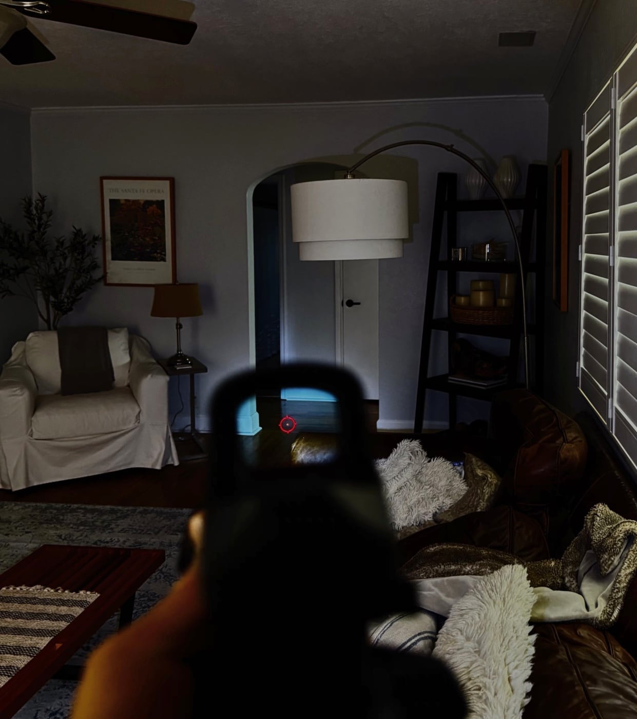 A person is shown moving through a dim or darkened home while holding a firearm equipped with a weapon-mounted light. The light is being used to see and identify potential threats or obstacles as the individual advances through hallways or rooms. This tactic is important in situations where intruders might be hiding or moving through the house during a home invasion. Navigating in low or no light conditions requires specialized equipment and training, especially when there are family members or pets that could be mistaken for a threat. Using a weapon-mounted light also allows the defender to keep both hands on the firearm, improving control and accuracy if needed. Learning how to survive a home invasion involves realistic practice with low-light tools and understanding when to use illumination without giving away your position. This approach ties together practical safety, home defense, and responsible firearm use under stress.