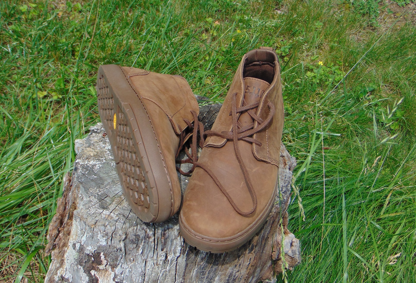 The image shows a pair of 5.11 Chukka Boots placed side by side, with one boot angled to display the sole’s tread pattern in detail. The boots feature a full-grain leather upper that looks smooth and flexible, while the Vibram outsole has a textured, non-slip design for solid traction. The stitching and craftsmanship are visible up close, emphasizing durability and everyday wear capability. These chukka boots are designed to work with both jeans and business-casual slacks, matching the low-profile tactical look discussed in the 5.11 Founder’s Jacket review. The image is used to highlight practical footwear options for security professionals and civilians alike. Overall, the boots are shown as comfortable, versatile, and ready for extended use.