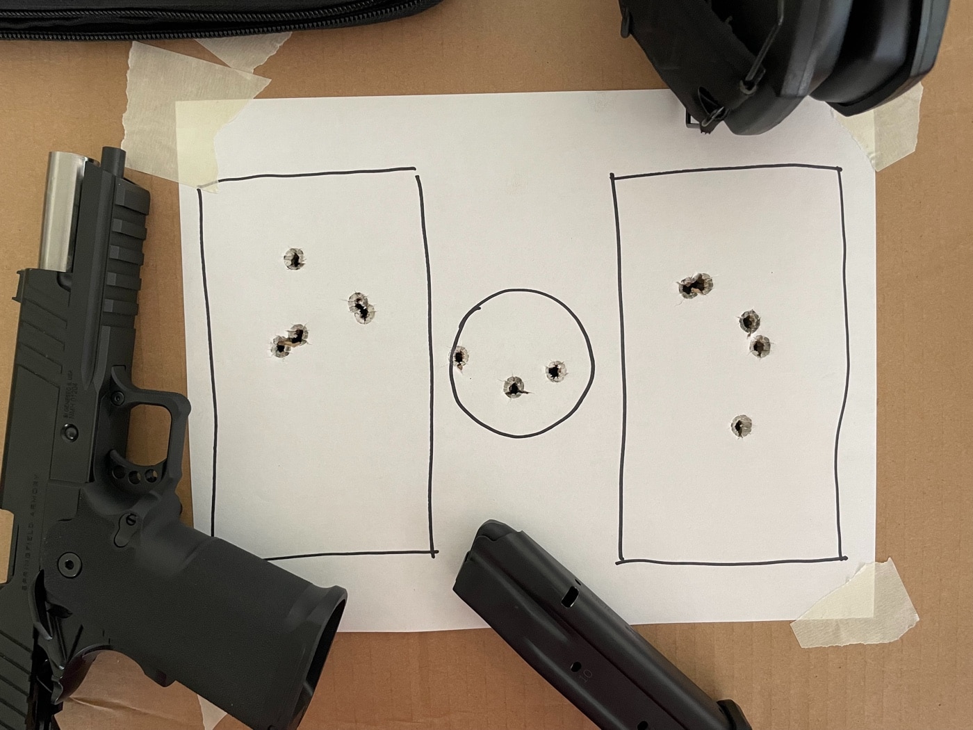 A Springfield Echelon handgun rests on a shooting bench beside a completed Baer Solutions training target, set in a public shooting range. The target is a standard 8.5”x11” sheet with two rectangular zones and a small center circle, each displaying bullet holes from a structured shooting drill. The pistol is unloaded and positioned safely, with its action open or magazine removed, following range safety protocols. Visible range elements like shooting stalls, target lines, and safety signage create a clear public range context. This image demonstrates the use of the Baer Solutions Standards Drill to balance speed and accuracy with a modern handgun. The clean, straightforward setup is typical for shooters working on measurable skill development. The photo fits articles about pistol training, public range best practices, and using professional drills for improvement.