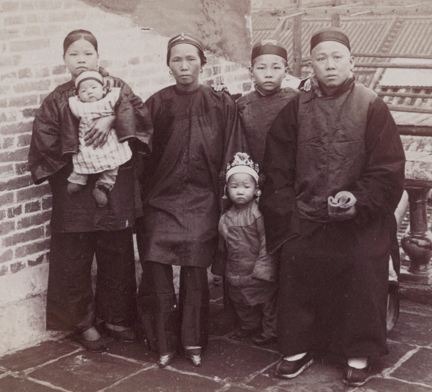 A Chinese Christian pastor is photographed with his family in Canton, China, in the early 1900s. The group includes the pastor, likely dressed in Western or semi-Western attire, and his wife and children standing or sitting beside him. The family appears somber and aware of the dangers they face as Christian converts in a society increasingly hostile to foreign influence. Their clothing and posture reflect both their faith and social position, set against a plain or modest domestic backdrop. This image illustrates the human impact of the Boxer Rebellion, when Chinese Christians were particularly vulnerable to violence and discrimination from Boxer militants. The pastor and his family embody the intersection of faith, cultural change, and political unrest in late Qing Dynasty China. Their story represents thousands of Chinese Christians who suffered during the uprising.