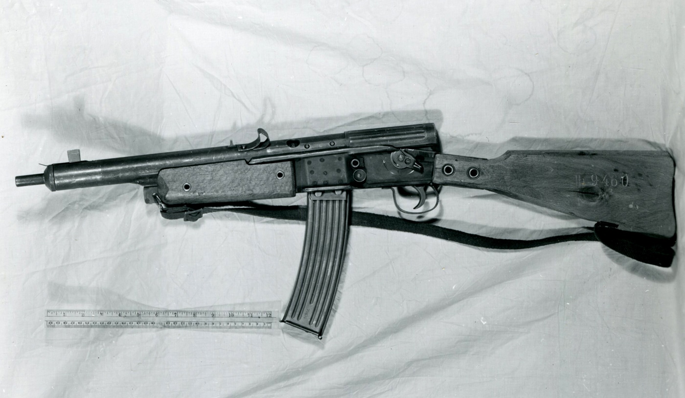 This close-up photograph provides a detailed look at the construction of a Gustloff Volkssturmgewehr rifle, focusing on the receiver, spring forms, and welded joints. The image clearly shows the simple machining marks, basic stamping, and minimal finishing applied to the metal parts, all features described by U.S. Ordnance in their late-war reports. Weld seams and riveted sections are prominent, underscoring the rifle’s emergency production origins. The springs and other internal components are basic in design, intended for ease of mass manufacture. Lighting highlights the industrial, utilitarian nature of the build. The photo was likely used in technical evaluations and archival records. This image is valuable for illustrating the technological compromises Germany made in producing firearms under extreme resource shortages. The overall impression is one of crude, effective functionality rather than refinement.
