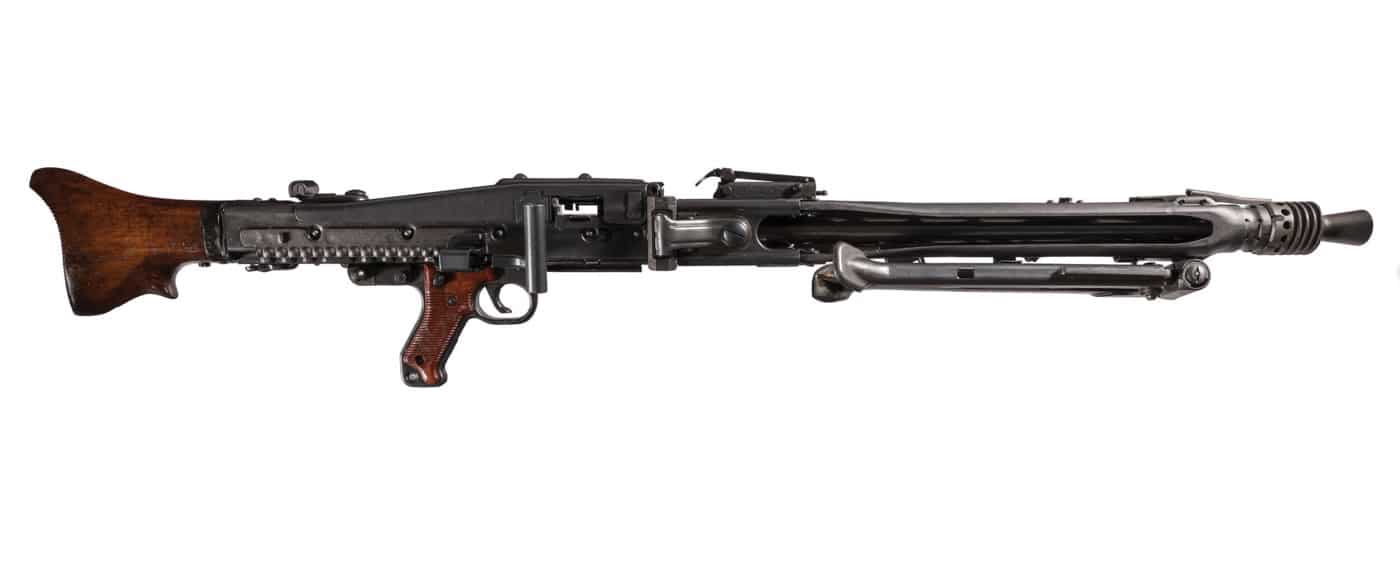 MG 42 machine gun displayed on a plain surface with its bipod extended. This is a German belt-fed general-purpose machine gun from World War II, sometimes called Hitler’s Zipper or Hitler’s Buzzsaw. The photo clearly shows the gun’s stamped steel receiver, barrel, and folding bipod. No accessories or extra gear are present. The weapon looks to be in good condition, with all main components visible, including the barrel shroud, pistol grip, and buttstock.