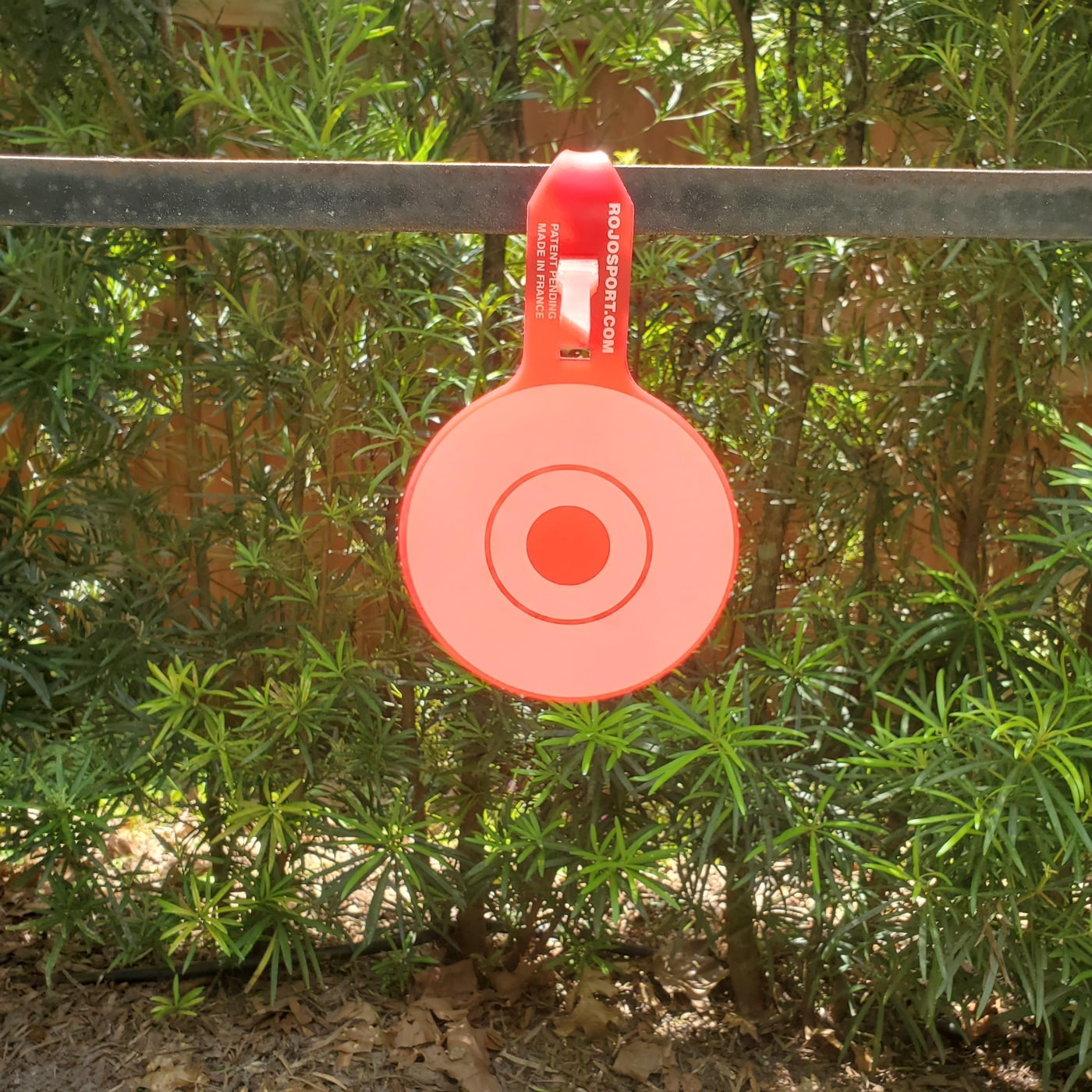 A close-up view captures the process of setting up the ROJO RJ4 Tactical Target, with hands securing the tail into its locking slot on a sturdy support. The screen-printed target face is clear, showing the bullseye and rings, while the background suggests a simple outdoor shooting range. The photo demonstrates the ease of installation as discussed in the Rojo RJ4 Tactical Target review. The setup looks straightforward, requiring no tools or extra hardware. This helps readers visualize exactly how to get the target ready for testing.