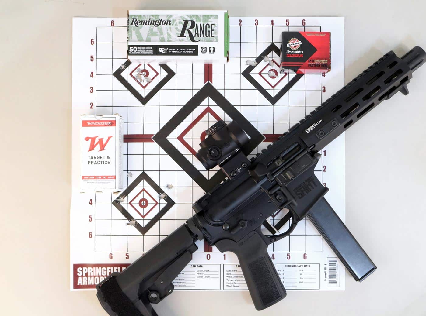A Springfield Armory SAINT Victor 8.5” 9mm pistol is displayed on a shooting bench beside several types of 9mm ammunition and a paper target showing tight, consistent shot groupings. The pistol is shown in use by the author during testing, with mixed loads from brands such as Federal and others. The target clearly demonstrates the pistol’s accuracy potential, even across different ammo types. The firearm remains clean and well-balanced, further supported by its AR-style controls and solid build. This image reinforces the performance claims made in the SAINT Victor 8.5” 9mm Pistol review, especially regarding reliability and precision.