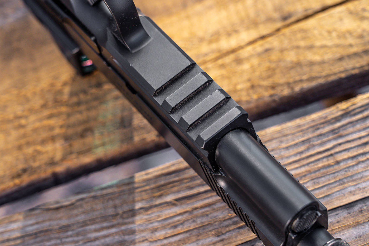 The image shows a detailed view of the accessory rail on the Springfield Armory 1911 Operator AOS, located on the underside of the frame just forward of the trigger guard. The machined grooves are clearly visible, allowing for the attachment of weapon lights, lasers, or other tactical accessories. The finish on the frame is smooth and matches the rest of the pistol, maintaining a consistent look. The rail is an integral part of the design, offering added functionality for those who may use the pistol in defensive or low-light situations. The background is either a table or shooting range surface. There are no additional objects in the frame, keeping the focus on the rail itself.