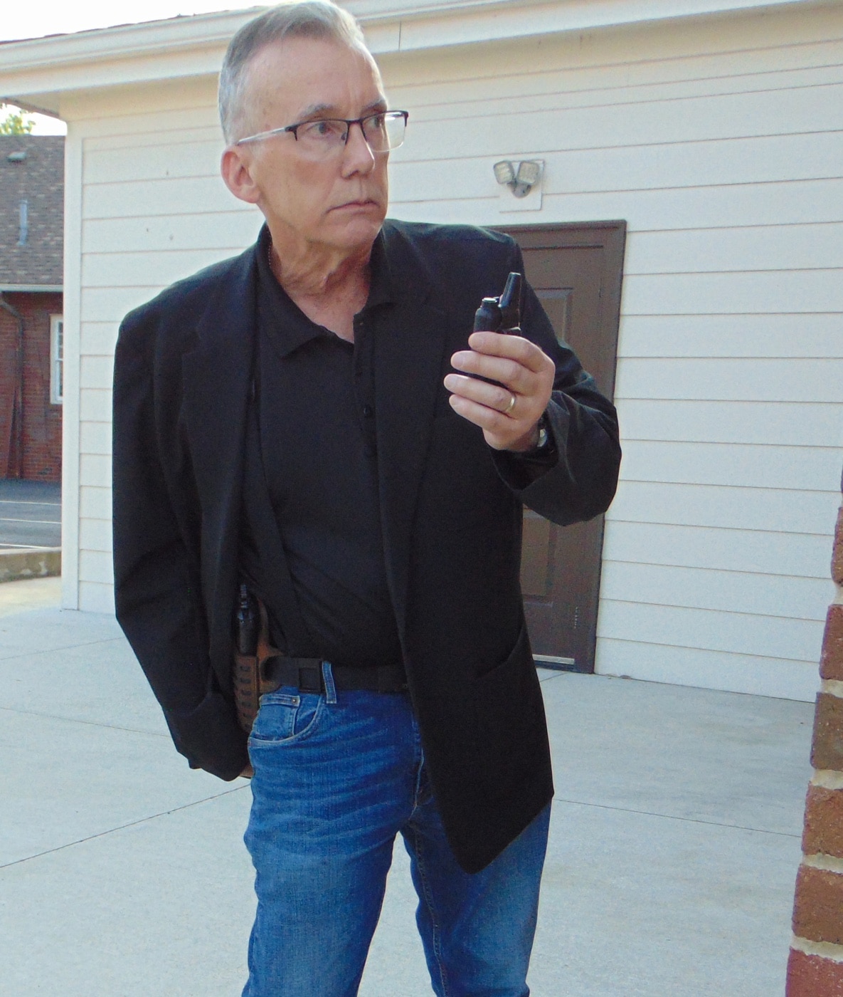 The photo captures the article’s author standing alert in a church lobby, dressed in the 5.11 Founder’s Jacket, as part of their volunteer church security role. The jacket fits comfortably and looks like a typical sport coat, with no visible signs of tactical gear or law enforcement accessories. The setting is bright and neutral, with people in the background unaware of the author’s role, showing how effectively the jacket blends in. The author’s hands are free, and nothing about the stance or clothing gives away the security function. This image demonstrates the Founder’s Jacket in a real-world concealed carry context, emphasizing its value for both security personnel and civilians who want to avoid attention. The photo supports the main points of the 5.11 Founders Jacket review, highlighting practical use and versatility.