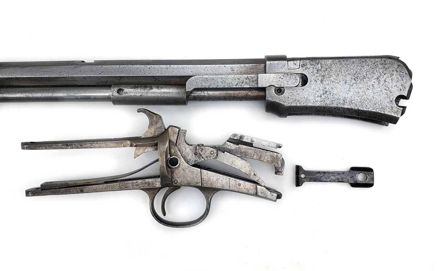 This image shows a collection of gun parts laid out on a clean towel or workbench after being soaked in a white vinegar bath to remove rust. The metal components — including the receiver, barrel, screws, and smaller pieces — appear noticeably cleaner than before, with the reddish-brown rust largely dissolved. Some areas may still show faint discoloration or pitting where corrosion was deep, but the majority of surfaces are now exposed bare metal or have a light gray finish. The arrangement lets viewers see the results of this simple cleaning process and how effective vinegar can be for restoring neglected firearm parts. The photo highlights the improvement over the earlier, rust-covered condition and sets the stage for further maintenance or refinishing steps.