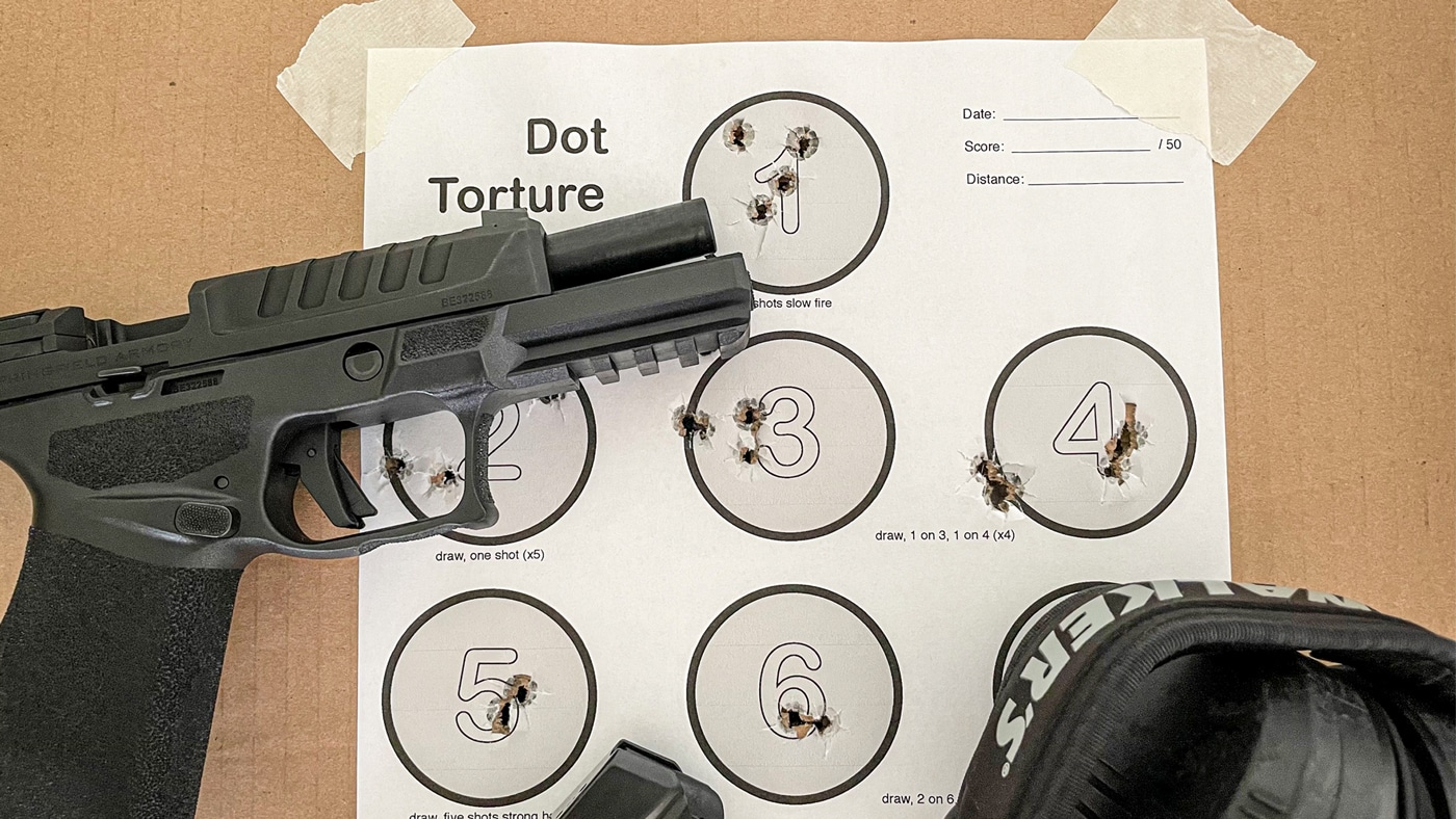 A Springfield Armory Hellcat Pro handgun rests on a shooting bench beside a completed Dot Torture paper target at an indoor gun range. The pistol is positioned slide-side up, with the target showing multiple shot groups in each numbered circle. There are visible spent casings and ear protection in the background, indicating a live fire training session. The Dot Torture target displays various shot patterns, reflecting focused marksmanship practice. This photo shows practical handgun training with a compact EDC firearm, focusing on improving accuracy, consistency, and trigger discipline.