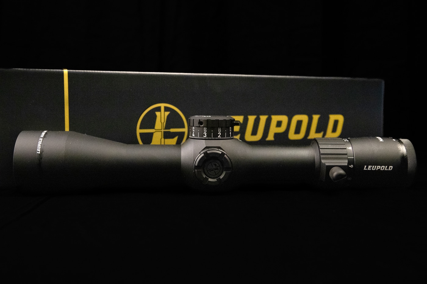 Detailed photo of the Leupold Mark 4HD 1.5-10x scope, focusing on the integrated throw lever and adjustment turrets. The throw lever is attached to the magnification ring, making it easier to change zoom levels quickly during shooting. Windage and elevation turrets are clearly labeled, with distinct, tactile clicks for precise adjustments. The scope’s matte black finish and robust construction are visible. This image highlights practical features that make the Mark 4HD 1.5-10x user-friendly for both tactical and hunting applications.