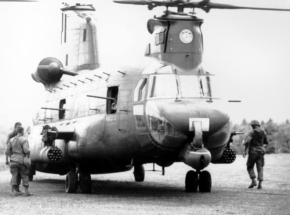 The image shows an ACH-47A Chinook assault helicopter, a rare armed variant of the CH-47 used during the Vietnam War. This version was equipped with 20mm cannons, rocket pods, grenade launchers, and multiple M60 or M2 machine guns. Its wide fuselage and tandem rotor blades are clearly visible, with weapons mounted on both sides of the airframe. The ACH-47A was part of the “Guns-A-Go-Go” program, intended to provide close air support and heavy firepower for U.S. Army troops. Only four of these helicopters were built, making them historically significant. The photo highlights the size and firepower of the aircraft in detail. The helicopter’s rugged design reflects its dual role as both a transport and a heavily armed gunship.