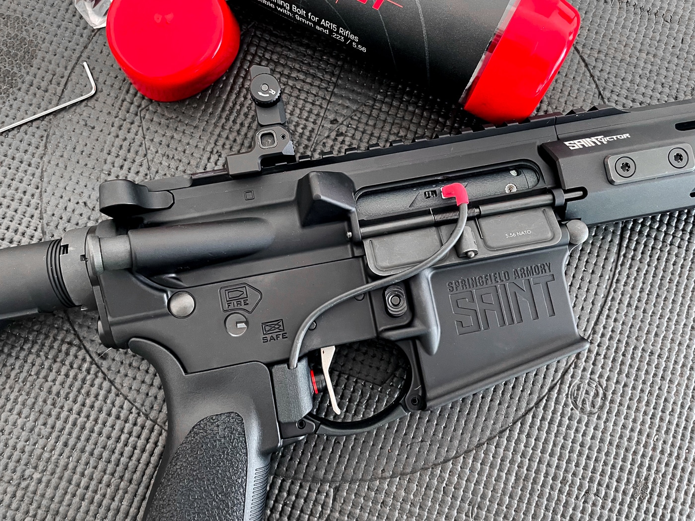 A Springfield Armory SAINT Victor AR15 rifle fitted with the Laser Ammo Flash Bolt dry-fire training system, shown on a tabletop with the upper and lower receivers assembled. The Flash Bolt is installed in place of the standard bolt carrier group. This version uses a red laser for target activation. The rifle’s black anodized finish contrasts with the small visible components of the Flash Bolt inside the receiver. The system enables repeated trigger pulls without manually cycling the rifle. The image demonstrates how the device fits seamlessly into a standard AR15 platform.
