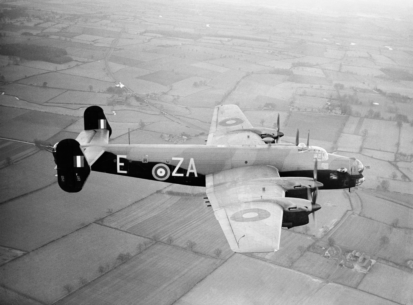 A Handley Page Halifax Mark II Series 1 early production model pictured without a nose turret. The absence of the forward gun position gives the aircraft a more aerodynamic nose, reflecting attempts to improve speed and reduce drag. This design choice, however, left the bomber more vulnerable to head-on attacks by enemy fighters. Later modifications reinstated the turret after crews reported operational losses. The image captures the Halifax during a transitional stage in its development, showing how wartime needs influenced aircraft design. The four-engine bomber otherwise retains its large wingspan, bomb bay, and characteristic fuselage layout.