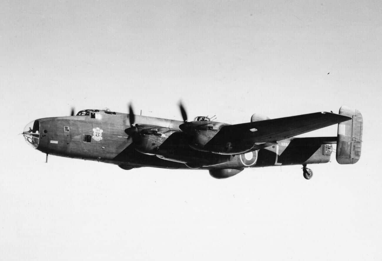 A Handley Page Halifax Mk II Series 1A bomber in flight during World War II. The aircraft is shown from a side angle, with its four engines powering the large bomber across the sky. This variant introduced key improvements, including a redesigned nose and enlarged tail fins, which improved handling and stability. The Halifax’s long fuselage and wingspan are clearly visible, reflecting its heavy payload capacity. The Series 1A model was one of the most common Halifax variants used during the RAF’s strategic bombing campaign. Its performance upgrades helped crews operate more effectively in dangerous nighttime missions. The photograph captures the Halifax in its operational environment, emphasizing both scale and power.