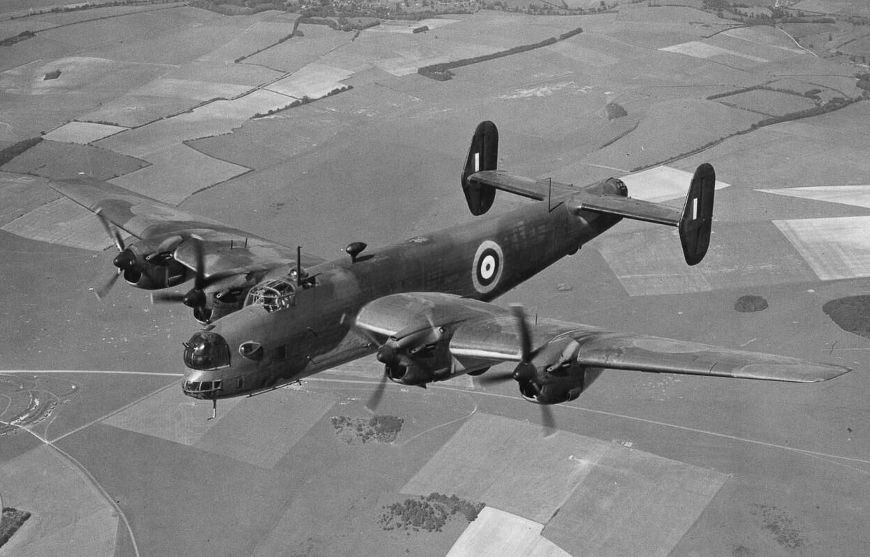 A Handley Page Halifax Mk I bomber in flight during World War II. This was the original production variant, powered by four Rolls-Royce Merlin X engines and fitted with a 22-foot-long bomb bay. The Mk I was equipped with defensive turrets in the nose and tail, carrying Browning machine guns for protection. Early examples had rounded tail fins, which were later replaced by square designs to improve handling. The Halifax Mk I could carry up to 13,000 pounds of bombs, making it a formidable addition to the RAF’s heavy bomber fleet. Although slower and less refined than later versions, it laid the foundation for the Halifax’s wartime role. The photo captures the bomber in level flight, showing its wingspan, fuselage, and engine configuration clearly.