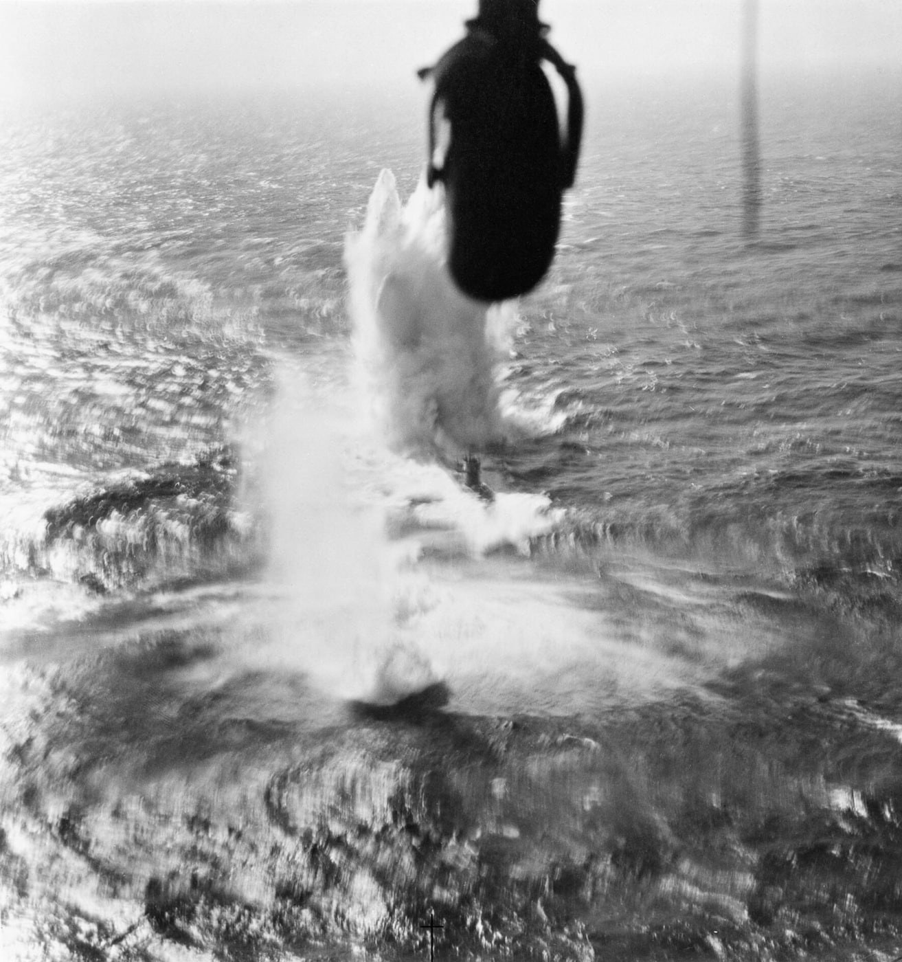 A dramatic photograph of a Handley Page Halifax heavy bomber attacking U-266, a German Type VIIC submarine, in the Bay of Biscay during World War II. The Halifax is seen in low flight as it releases depth charges or bombs toward the surfaced U-boat. The German submarine is visible below, caught in the open sea while attempting to transit the dangerous Bay of Biscay. Halifax bombers were adapted for anti-submarine warfare, equipped with radar and depth charges for missions like this. The attack demonstrates the versatility of the aircraft, which served not only as a heavy bomber but also in maritime reconnaissance and patrol roles. Such missions were critical to reducing U-boat effectiveness against Allied convoys. The photograph captures the intensity of the battle between RAF Coastal Command and Germany’s submarine fleet.