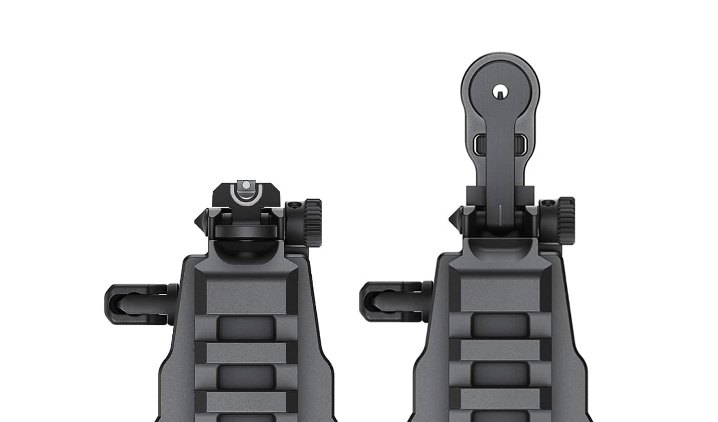 A close-up comparison of Springfield Armory Kuna’s hybrid flip-up sights shown in two positions. On the left side, the sight is folded down, presenting a compact U-Dot style rear with a bright front dot for quick aiming. On the right side, the sight is flipped up, revealing a more traditional iron sight arrangement with a clear aperture and front post. The contrast highlights how the system moves from a low-profile defensive sight to a precise aiming tool. The photo emphasizes the difference in sight radius and sight picture. This dual setup demonstrates versatility for both close-quarters and extended-range shooting. The overall finish is metal, showing durability and quality construction.