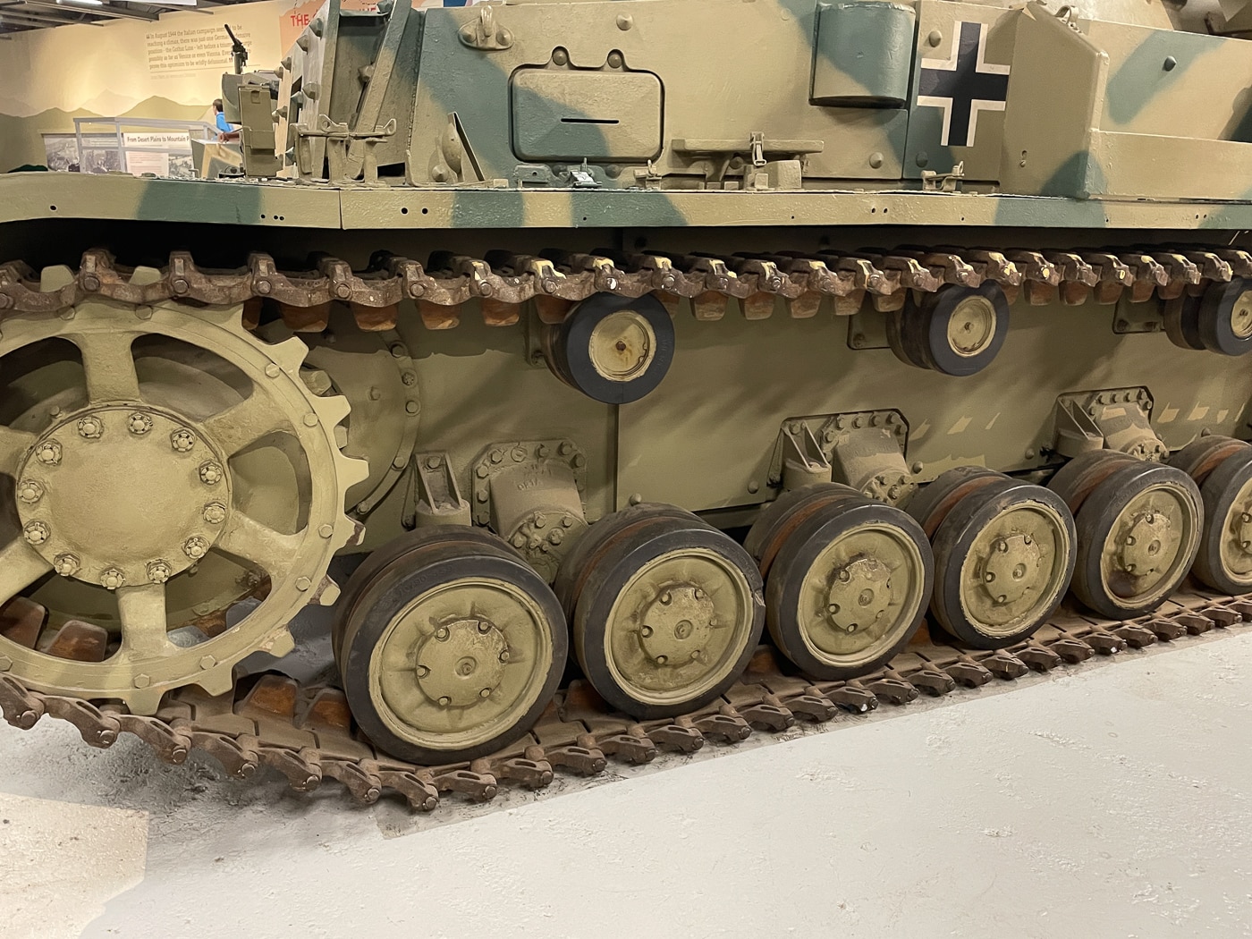 The photograph shows a close-up view of the Panzer IV’s suspension system, which played a major role in its stability as a gun platform. Visible are the tank’s eight small, rubber-rimmed road wheels on each side, mounted in paired bogies. Each bogie is supported by leaf springs, which helped absorb shock and maintain steady movement over rough terrain. The track links are partially visible, showing the contact area between the suspension and the ground. This configuration allowed the Panzer IV to keep its 75mm gun on target more effectively while on the move compared to many contemporaries. The image captures the mechanical layout from the side, clearly showing how the suspension’s design balanced durability and ride quality.