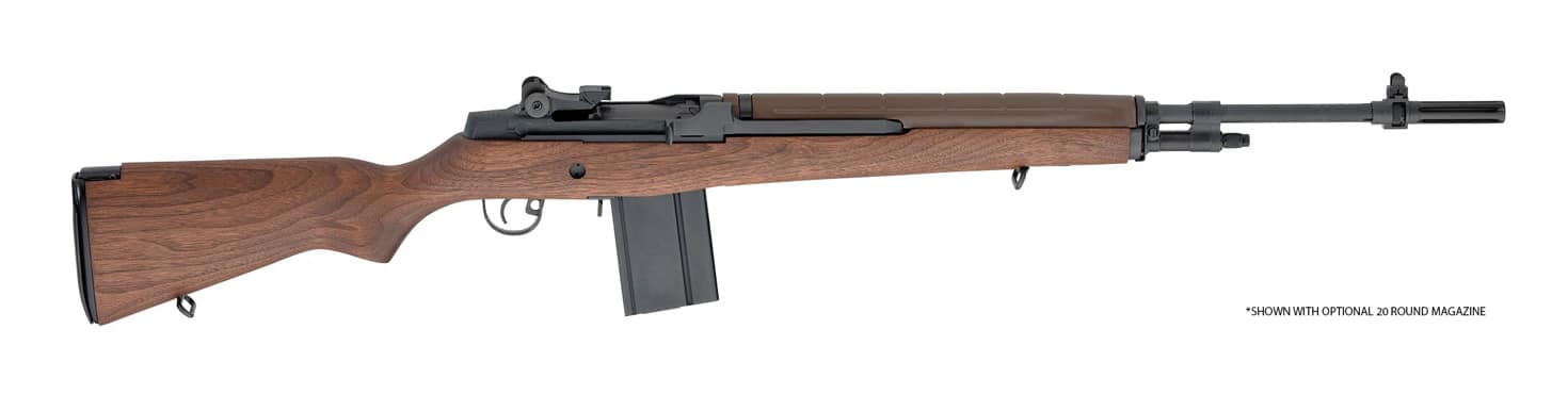 This photo features a Springfield Armory M1A rifle displayed alone against a plain, neutral background, making its features stand out. The rifle’s full-length walnut stock is prominent, showing the classic wood grain pattern associated with U.S. military rifles. The parkerized steel barrel, receiver, and iron sights are clearly visible along the top of the rifle. Details such as the two-stage trigger, long sight radius, and hinged butt plate are easy to identify in the well-lit image. The M1A’s magazine is inserted, emphasizing its semi-auto capability and military-inspired look. There are no props or distractions, allowing viewers to focus on the craftsmanship and historical design cues of the firearm. This image is ideal for articles about the Springfield M1A, civilian versions of the M14, or classic American service rifles.