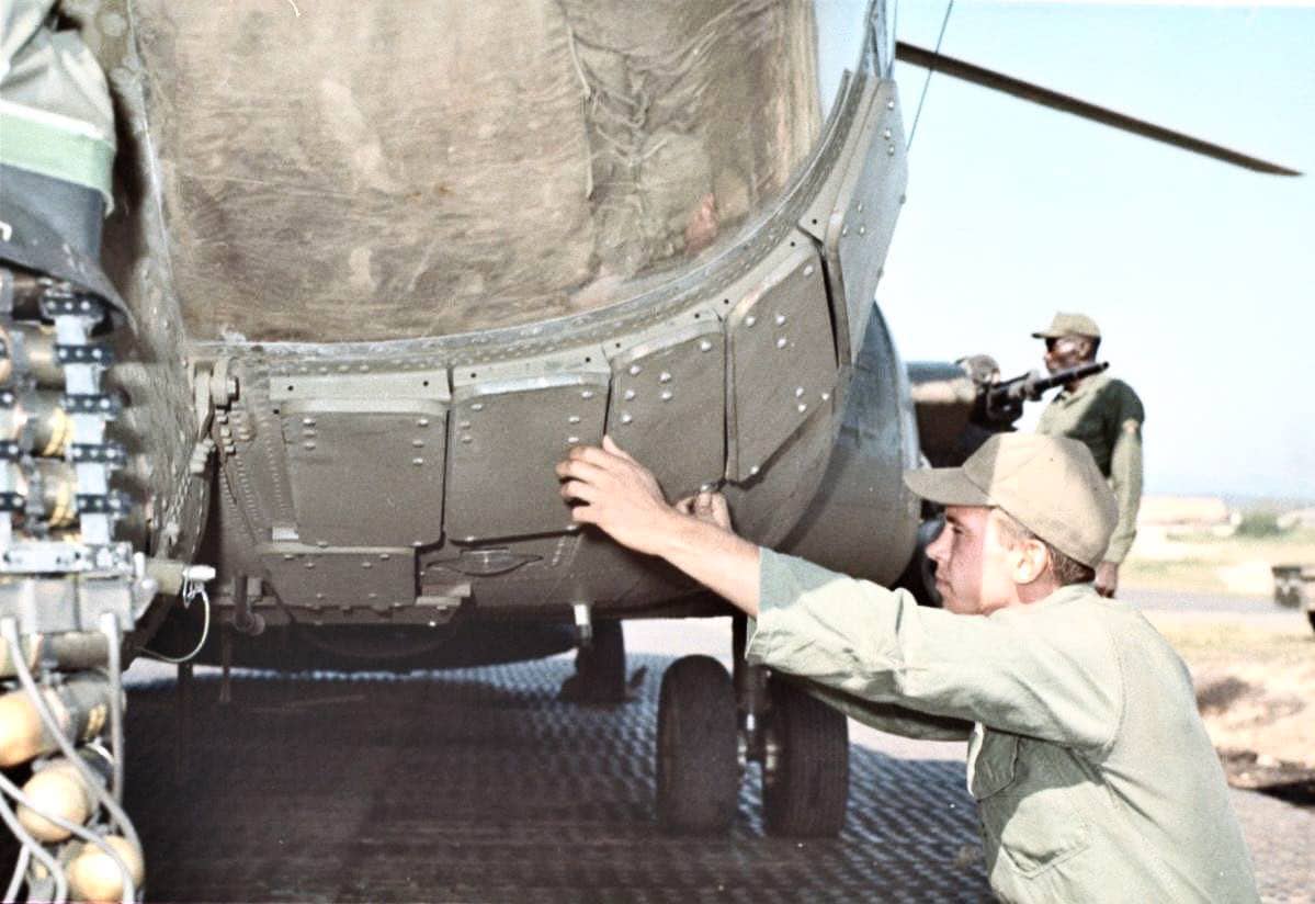 The photo shows a U.S. Army soldier closely inspecting the armor plating on the side of an ACH-47A Chinook gunship. This armor was fitted to protect critical systems such as the cockpit, engines, and hydraulic lines from small arms and shrapnel damage. The ACH-47A’s design included additional armor integrated into specially designed crew seats for the pilot and co-pilot. The soldier appears to be checking for wear, damage, or secure fastening of the plating. These pre-flight inspections were vital to ensure the helicopter could survive intense enemy fire during missions. The image highlights the rugged modifications that separated the ACH-47A from standard CH-47 transport models. The presence of heavy weapons and armor made this helicopter a unique battlefield asset during the Vietnam War.