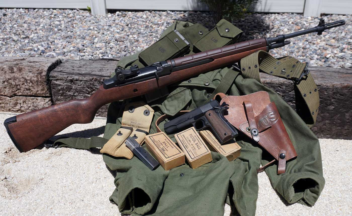 This image displays the Springfield Armory M1A rifle alongside the Springfield Armory Mil-Spec 1911 handgun. The two firearms are laid out together, showing the contrast between the larger walnut-stocked semi-automatic rifle and the parkerized steel .45 ACP pistol. The M1A features a traditional wooden stock and parkerized metal components, while the Mil-Spec 1911 shows off its checkered grips and classic military styling. Both guns are well-lit and clearly visible, emphasizing their condition and construction. The background is neutral and unobtrusive, keeping the focus on the firearms. This photo would be suitable for any article discussing the Springfield M1A and M1911 Mil-Spec, U.S. military-inspired firearms, or classic American service weapons. These Springfield Armory models are modern, accessible alternatives for collectors and shooters interested in American military history.
