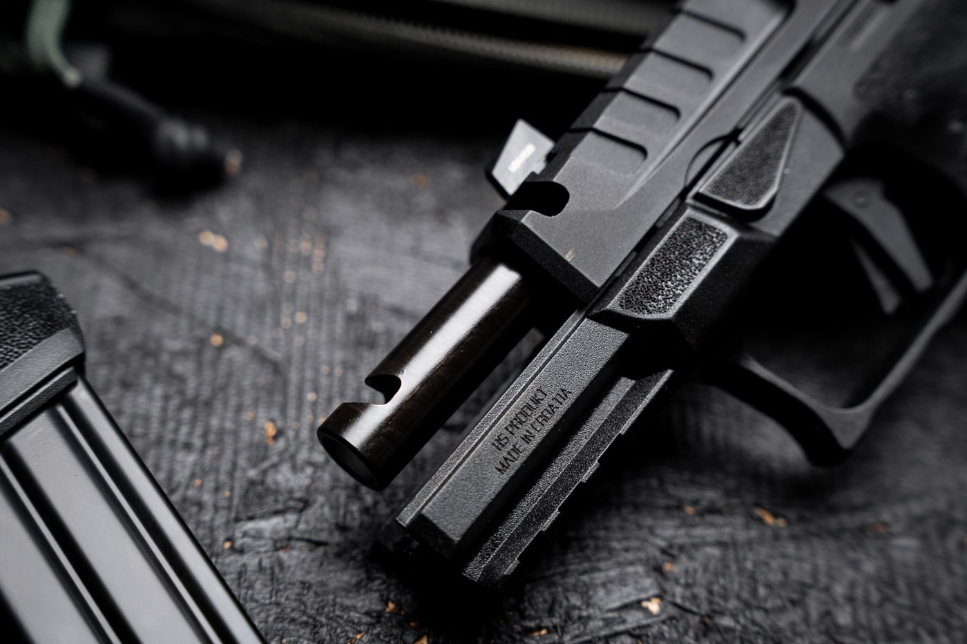 A detailed image of the Springfield Armory Echelon 4.0C Comp pistol’s integral single-port compensator cut. The port is machined directly into the front of both the slide and barrel, allowing high-pressure gases to vent upward to counter muzzle rise during firing. The compensator is located just behind the tritium/luminescent front sight, with precise alignment between barrel and slide cuts. The black Melonite finish covers the entire surface, highlighting the clean machining and rugged build quality. Serrations at the front of the slide offer additional grip for press checks. This integral design eliminates the need for an extended threaded barrel or aftermarket attachment. The photo focuses on the compensator’s functional role in improving recoil control for faster follow-up shots.
