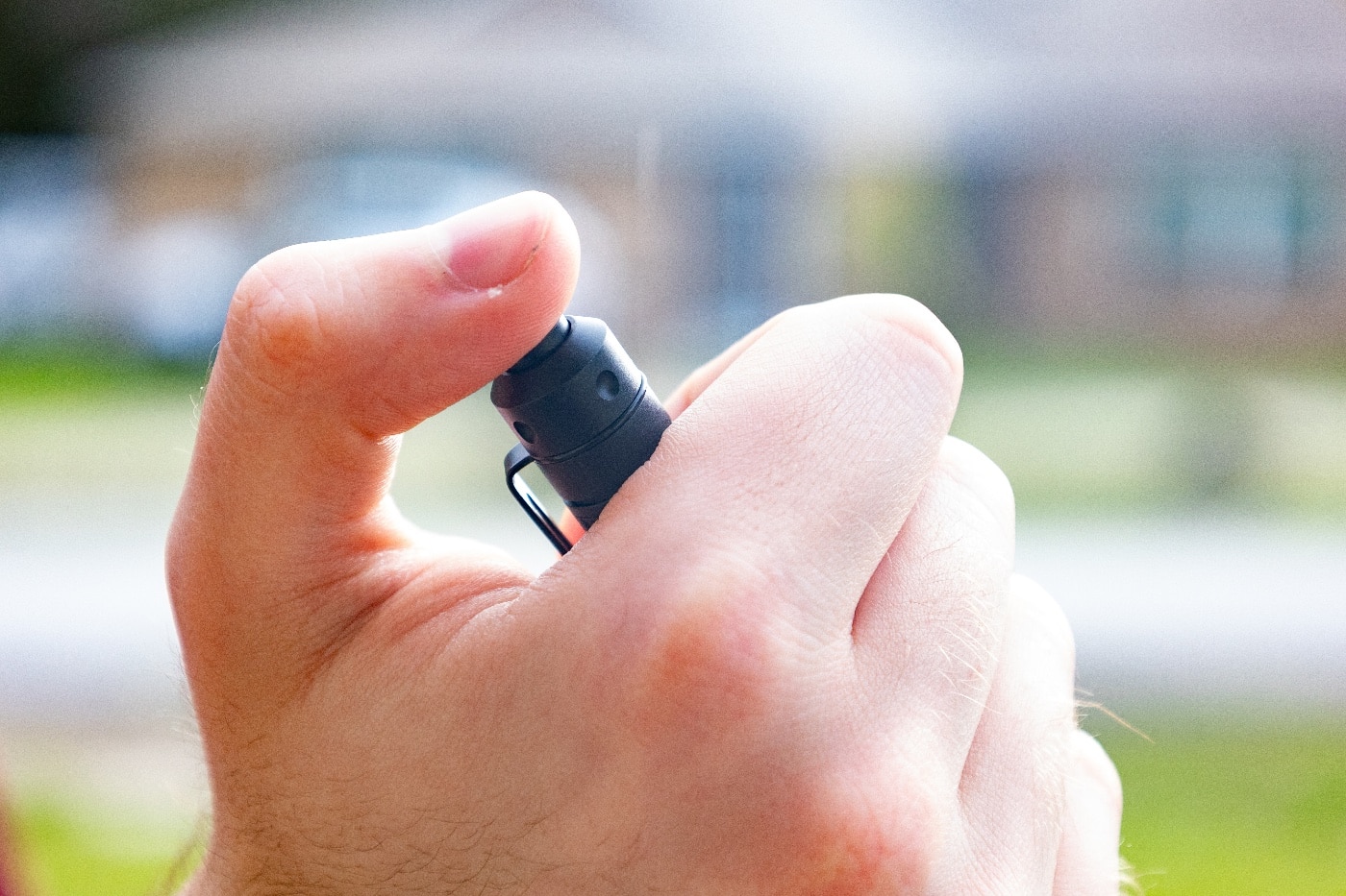 Image of the Princeton Tec Alloy-X flashlight’s rear-mounted clicky button. The switch is positioned at the tail end of the light for easy thumb operation. It is constructed from a rigid polymer material and provides both momentary-on and constant-on functionality. A half-press activates the light temporarily, while a full click turns it on continuously. Repeated clicks cycle through the flashlight’s output modes: medium, low, and high. The button has a slightly raised, textured surface for better grip. This control design is simple but effective for everyday carry use.