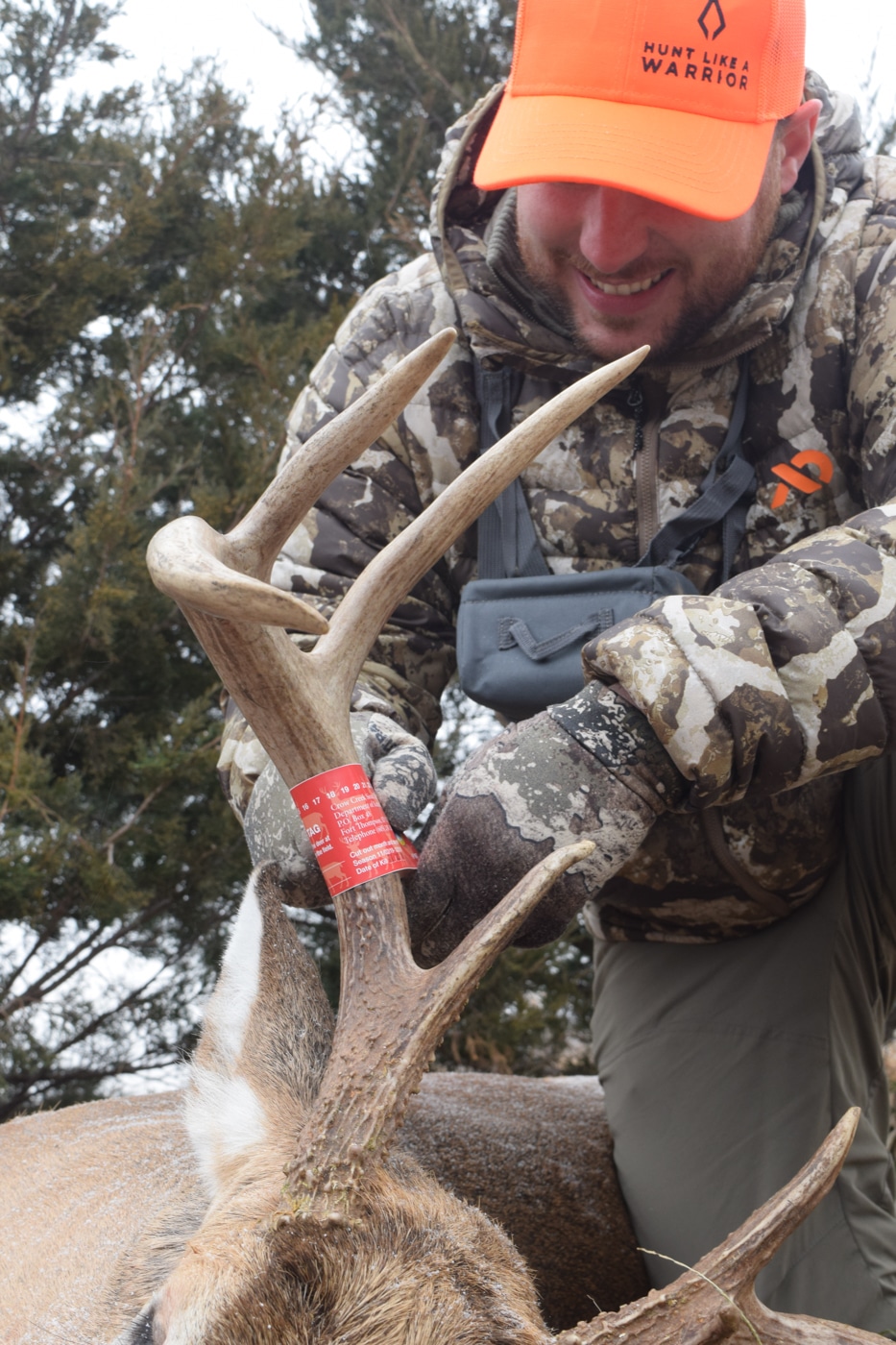 A harvested whitetail deer lying on the ground in a natural outdoor setting, with autumn leaves and dry grass around it. The animal is intact with no visible excessive damage, indicating a clean kill. The hunter is not visible in the frame, keeping focus on the game. This deer was taken using Barnes Harvest Collection ammunition loaded with a Sierra Tipped GameKing bullet, known for controlled expansion and rapid energy transfer. The setting suggests a typical deer hunting environment in the fall season. The image illustrates the real-world hunting effectiveness of the TGK bullet design.