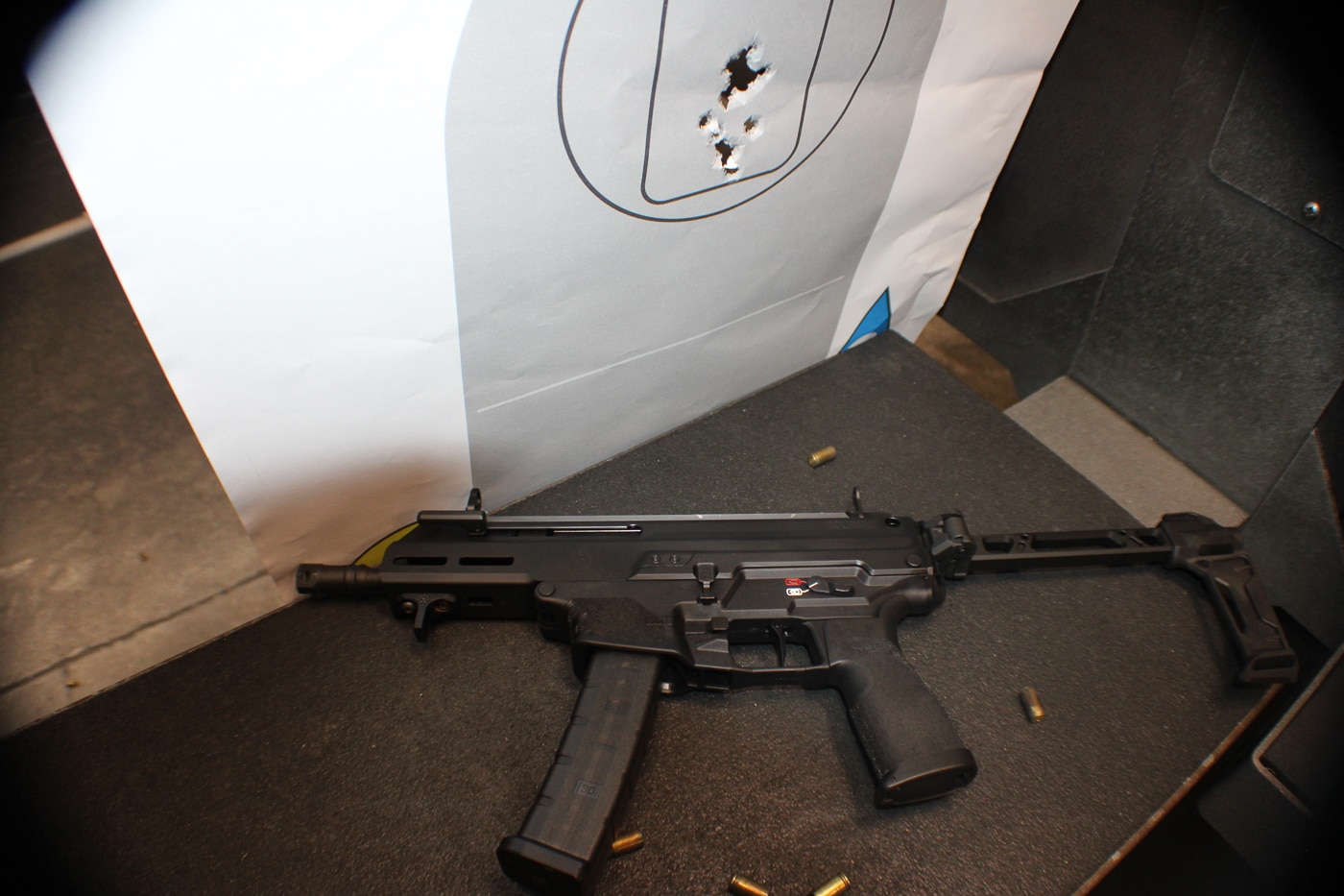 A photo of a paper target displaying consistent hits in the A-zone, demonstrating the precision of the Springfield Armory Kuna’s hybrid sights. The tight grouping shows that the sight system is effective beyond close range, maintaining accuracy during controlled drills. The image highlights how the aperture and post setup, when flipped up, allow shooters to center their shots reliably. This visual evidence supports the firearm’s role as more than just a compact PDW but as a capable defensive weapon. The target’s markings and clean shot placement emphasize the stability of the sight picture. The results show that Springfield’s hybrid design can hold zero and deliver confidence. The photo reinforces the firearm’s dual-purpose capability for both speed and accuracy.
