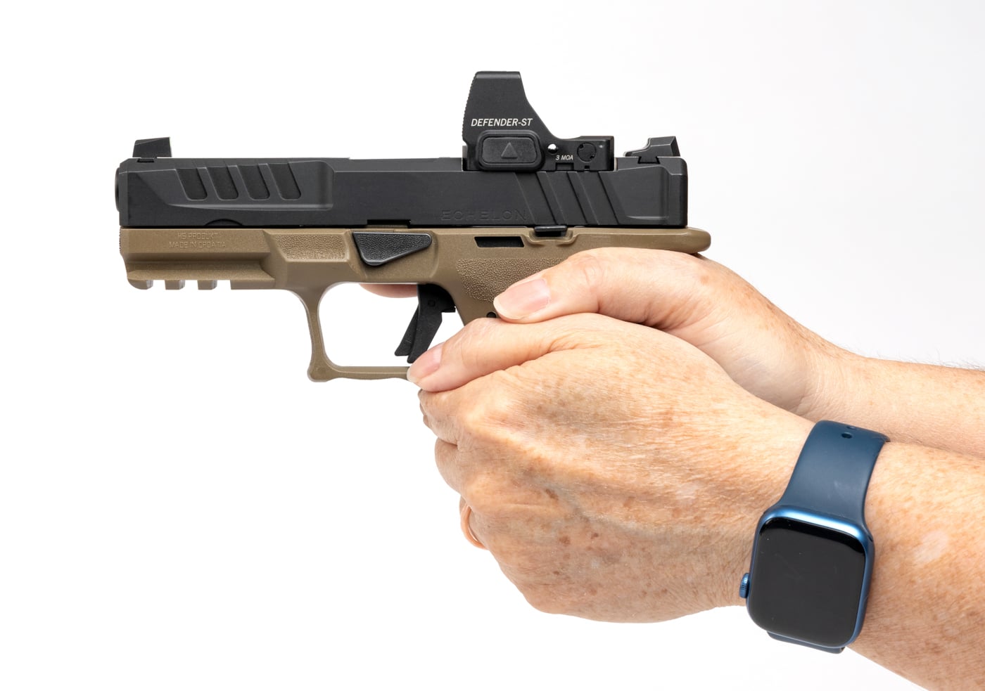 The image shows a person holding several Springfield Echelon 4.0C grip modules, trying each one in hand to find the best fit. The person is comparing the small, medium, and large grip modules, feeling for comfort and checking how the backstrap and trigger reach align with their hand. The modules are polymer and come in different sizes to accommodate various hand shapes and preferences. The focus is on the hands and grip modules, highlighting the process of finding a proper ergonomic match. The workspace is well-lit and organized, with additional grip modules visible on the table. This image demonstrates the practical, hands-on approach to selecting a grip module, which can improve both comfort and shooting accuracy. It’s a useful reference for anyone considering an upgrade or customization to their Echelon 4.0C.