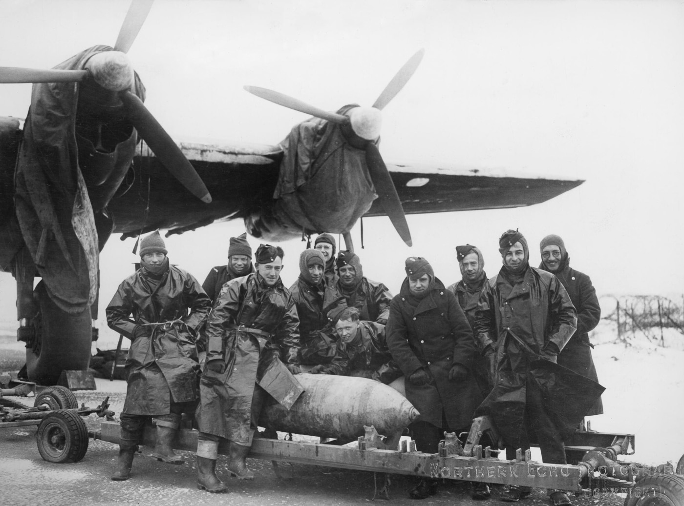 Ground crews load a 500-pound bomb beneath a Handley Page Halifax Mark II during winter, with snow visible around the aircraft. Several men work in heavy coats, positioning the bomb carefully onto the loading trolley. The Halifax looms above them, its engines and undercarriage standing out against the cold background. The bomber’s large bomb bay allowed it to carry heavy payloads, often mixing 500-pound bombs with larger weapons. This photo highlights the difficult working conditions faced by ground staff, who prepared aircraft in freezing weather. Despite the harsh environment, bomb loading and mission readiness continued without interruption. The Halifax Mk II was one of the primary models in use at this stage of the war.