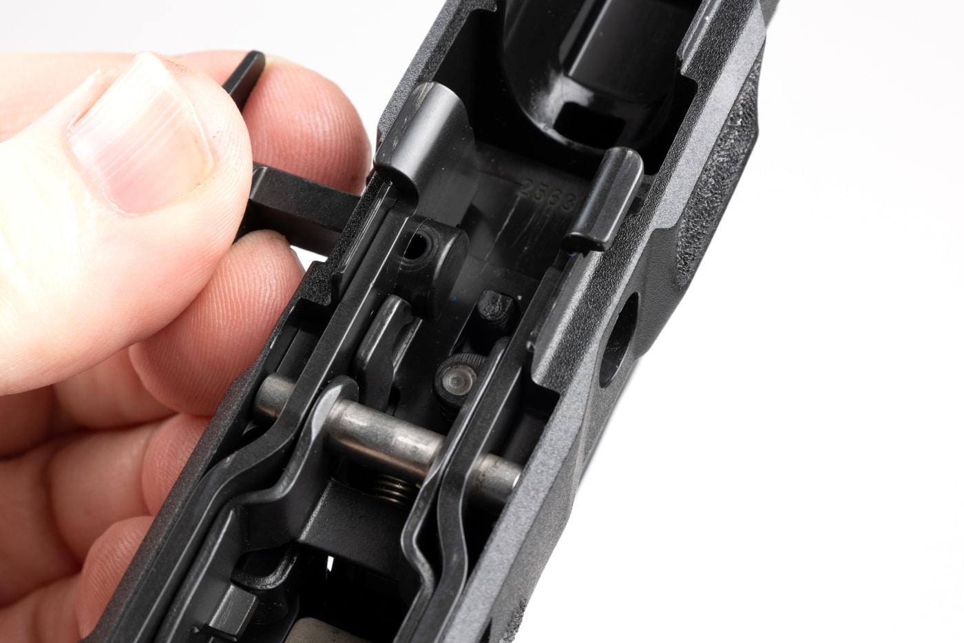 The image shows a close-up of a hand pulling the disassembly lever out from the left side of a Springfield Echelon 4.0C grip module. The hand is using a firm grip and is in the process of twisting the lever in a clockwise direction, as recommended by Springfield’s instructions. The slide has already been removed, and the area around the lever is clearly visible. This motion releases the disassembly lever from the Central Operating Group, allowing for removal or replacement of the grip module. The photo demonstrates the resistance that might be felt, which is normal and ensures the components are secure during use. The workspace is neat, with good lighting to show all mechanical details of the process. The image is a practical reference for anyone learning how to disassemble or modify the Echelon 4.0C.