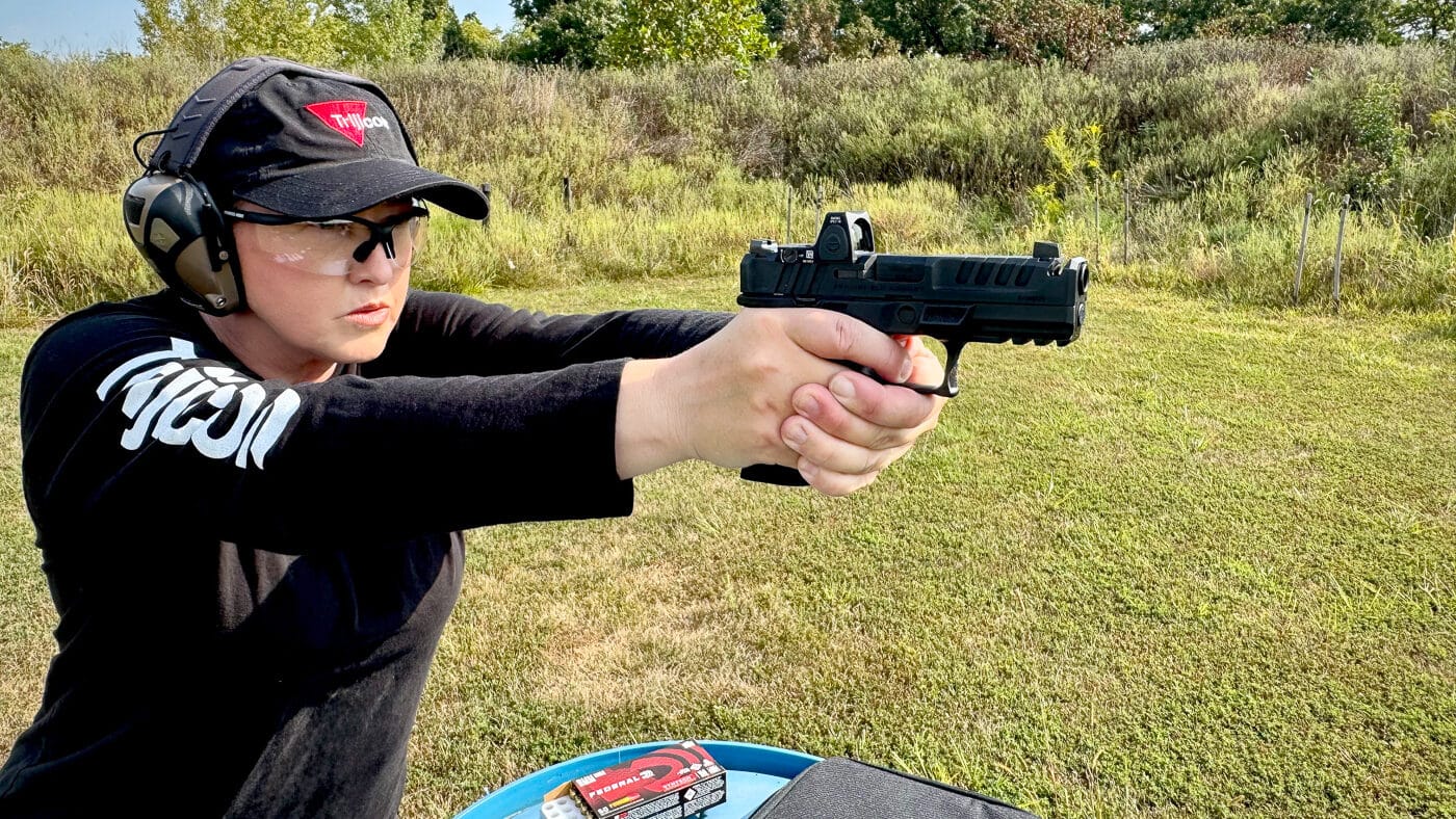 A shooter is firing a Springfield Armory Echelon pistol outfitted with a Trijicon RMR reflex sight featuring the green LED dot reticle. The handgun sits low in the hands, showing the compact design of the RMR Type 2 mounted directly to the slide. The optic’s green dot provides faster sight acquisition and increased visibility compared to traditional red dots. The pistol’s ergonomic frame and slide serrations are clearly visible. The setup demonstrates how the RMR maintains co-witness with standard height iron sights. The image captures the optic’s practical use during live fire training, emphasizing durability and clarity.