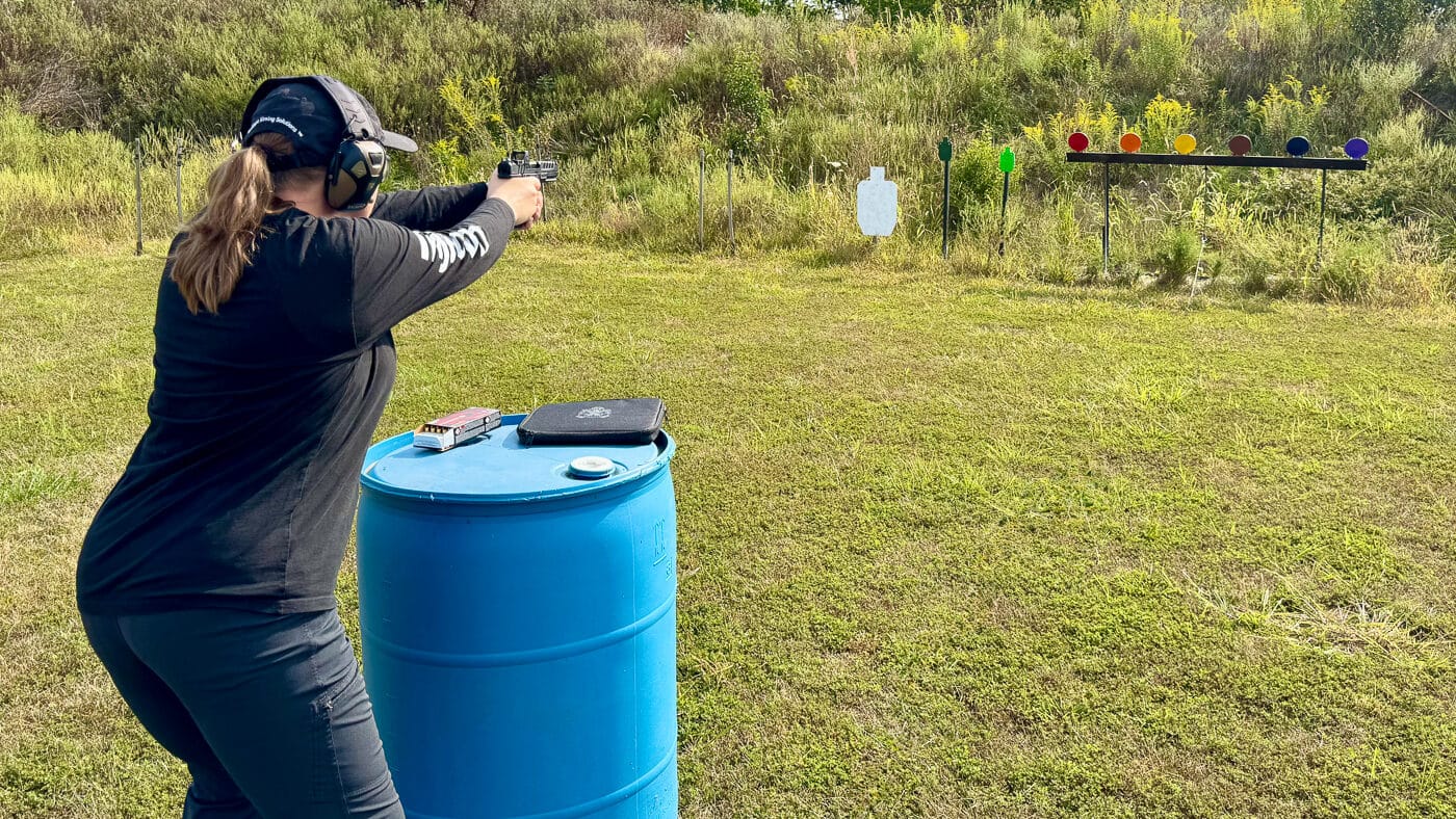 A competitive shooter, Julie Golob, is pictured testing a handgun equipped with the Trijicon RMR reflex sight featuring the green LED dot. The optic is mounted low on the slide, showing how it integrates seamlessly with the Springfield Armory Echelon platform. The green dot reticle is designed for quicker acquisition and improved clarity over red dots, especially in bright or low-light environments. Julie is actively evaluating the optic’s performance in live fire. The RMR’s distinctive housing with protective ears is visible, emphasizing its durability. This setup showcases the optic’s practical use for competition, hunting, or defensive applications.