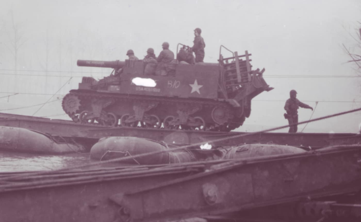 An American M12 Gun Motor Carriage is pictured crossing a pontoon bridge in February 1945. The vehicle carries its 155mm cannon forward, locked into position for movement. The bridge consists of floating pontoons and a deck strong enough to support the heavy chassis. The open crew compartment is visible, showing the exposed design that left artillerymen vulnerable despite the vehicle’s size. Engineers played a critical role in enabling such crossings, keeping heavy self-propelled artillery close behind advancing troops. The M12 was essential for supporting attacks on fortified positions as U.S. forces pushed deeper into Germany. This photo captures both the mobility and logistical demands of employing one of America’s heaviest artillery vehicles.
