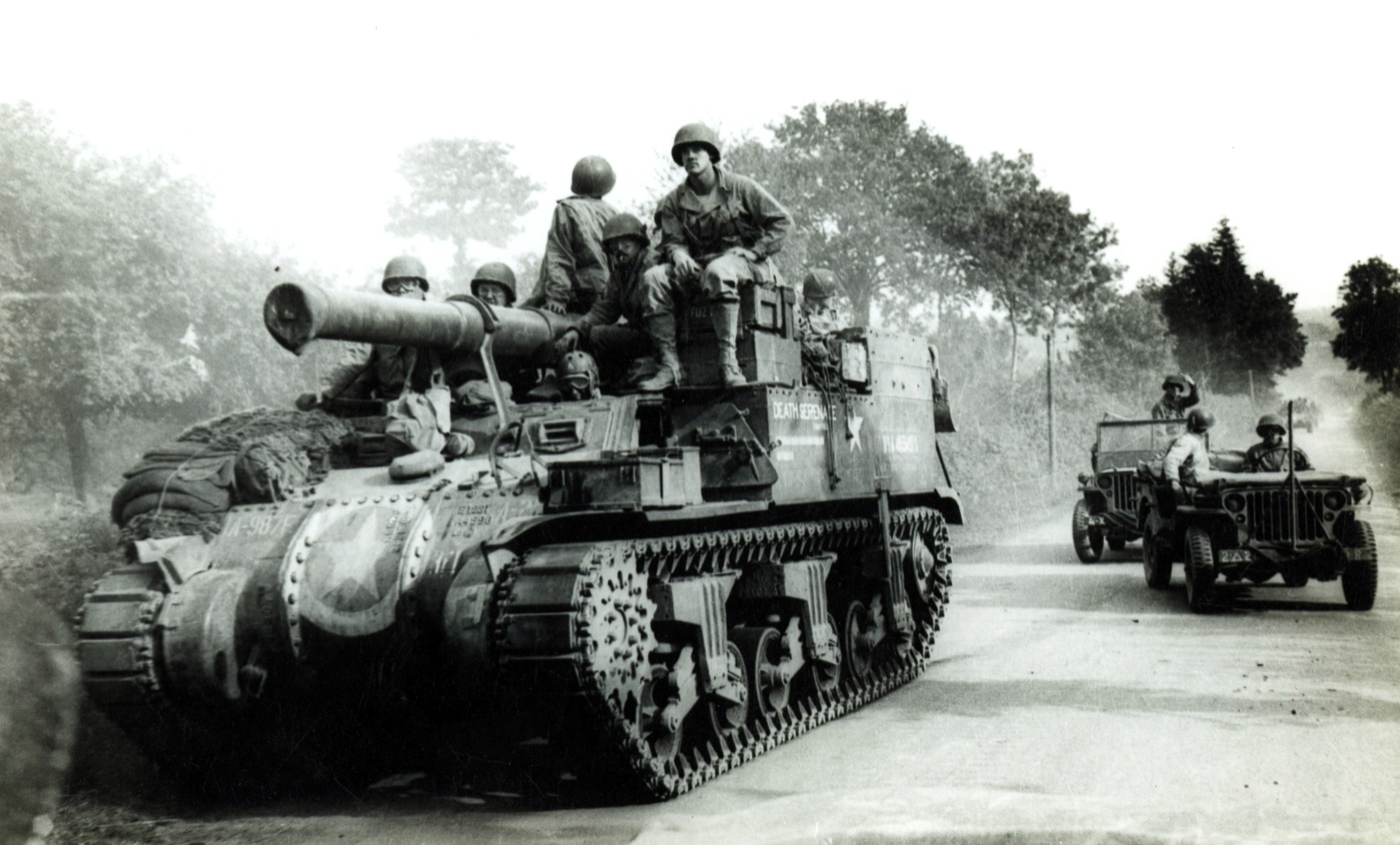 A U.S. Army M12 Gun Motor Carriage is pictured in France during the late summer of 1944, with its 155mm gun secured in a forward-facing travel lock. The vehicle sits on the M3 tank chassis, easily identifiable by its suspension system and elongated body. Unlike a turreted tank, the M12’s open fighting compartment left the crew exposed, which was acceptable when the gun was on the move. The travel lock was essential for protecting the long cannon barrel during transport across rough terrain. This photo reflects how the M12 was frequently repositioned to provide artillery support during the breakout from Normandy and the push across France. Its role as a mobile heavy gun distinguished it from towed artillery, giving American forces flexibility in battle. The image highlights both the size of the weapon and the engineering adjustments needed to make it mobile in combat conditions.