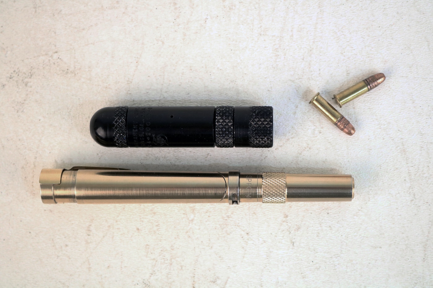 The image shows a side-by-side comparison of the MAC Stinger and the Braverman Stinger. The MAC version is a short cylindrical firearm that looks like a metal tube, while the Braverman pen gun more closely resembles a folding ink pen when collapsed. Both guns fire .22 caliber rimfire ammunition and were marketed for deep concealment. The MAC Stinger was developed in the 1970s by the Military Armament Corporation, while the Braverman appeared later with a design focused more on disguise. The comparison highlights the different approaches to covert firearms during the Cold War era. Despite their novelty, both guns were considered unsafe and impractical for real-world use. Today, they are classified by the BATF as Any Other Weapon (AOW) and are sought after as collector items.