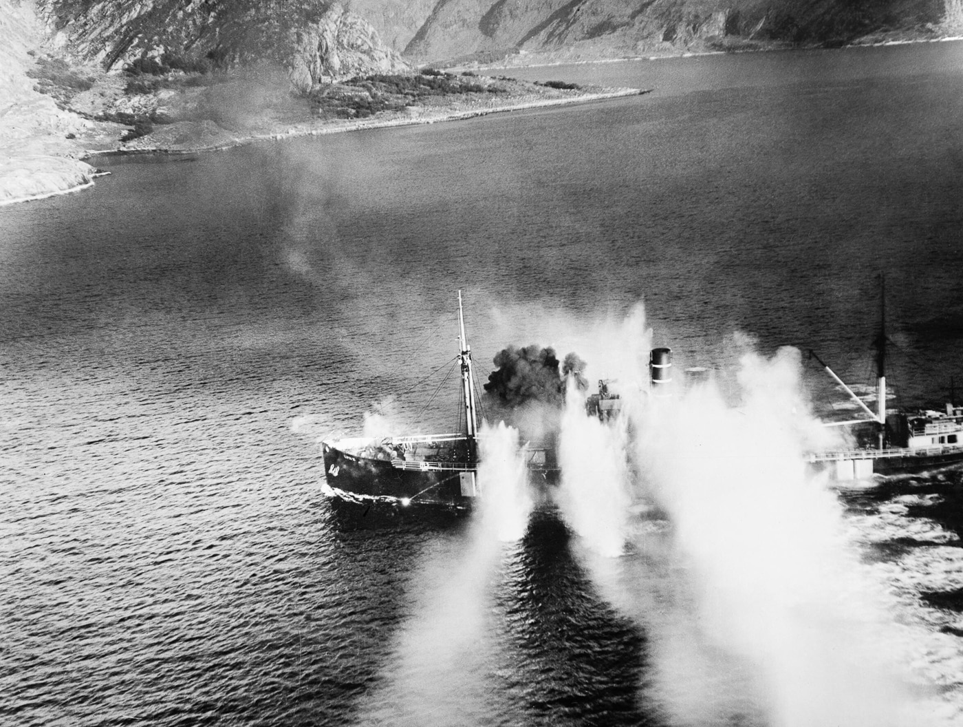 An oblique aerial photograph taken on 19 September 1944 during a Royal Air Force attack on the Norwegian merchant vessel LYNX in Stav Fjord. The image shows explosions erupting on the 1,367-ton ship after direct rocket projectile hits. The attack was carried out by Bristol Beaufighters and de Havilland Mosquitos of the Banff Strike Wing, a coastal strike force based in Scotland. The photograph captures the moment of impact, with smoke and debris rising from the ship’s deck. This coordinated strike sank the LYNX, part of the broader RAF effort to disrupt German supply lines and shipping in occupied Norway. The image reflects the precision and destructive capability of rocket-armed Mosquitos and Beaufighters. It is both a combat record and a visual reminder of the dangers faced by Axis shipping.