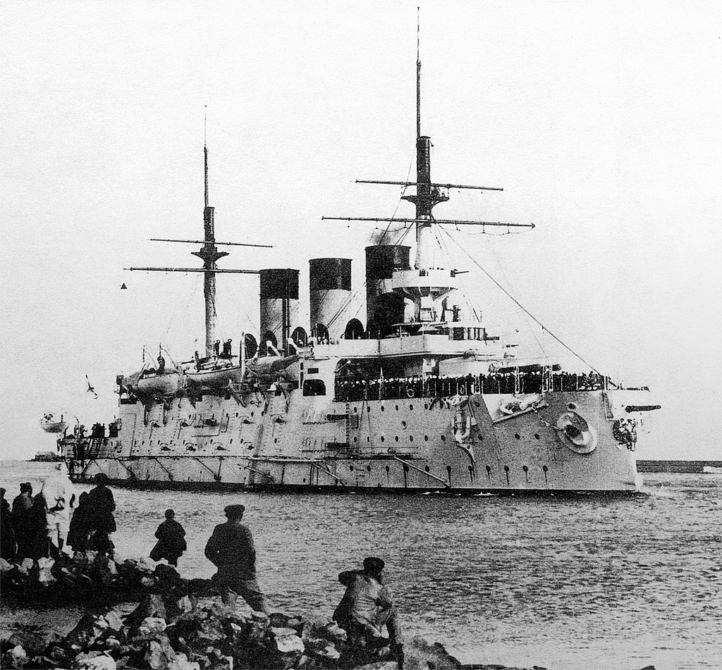 The photo shows the Russian battleship Oslyabya, a pre-dreadnought warship of the Imperial Russian Navy, underway before the Battle of Tsushima in 1905. She features a heavy steel hull, multiple gun turrets, and a central superstructure with two tall funnels. At Tsushima, Oslyabya became the first major loss of the battle, sinking after sustained Japanese shellfire. The ship went down quickly, with hundreds of sailors trapped aboard. Her loss marked the beginning of a disastrous day for the Russian Second Pacific Squadron. The image reflects the outdated design and poor condition of many Russian battleships at the time. Oslyabya’s sinking symbolized Russia’s vulnerability in modern naval warfare.