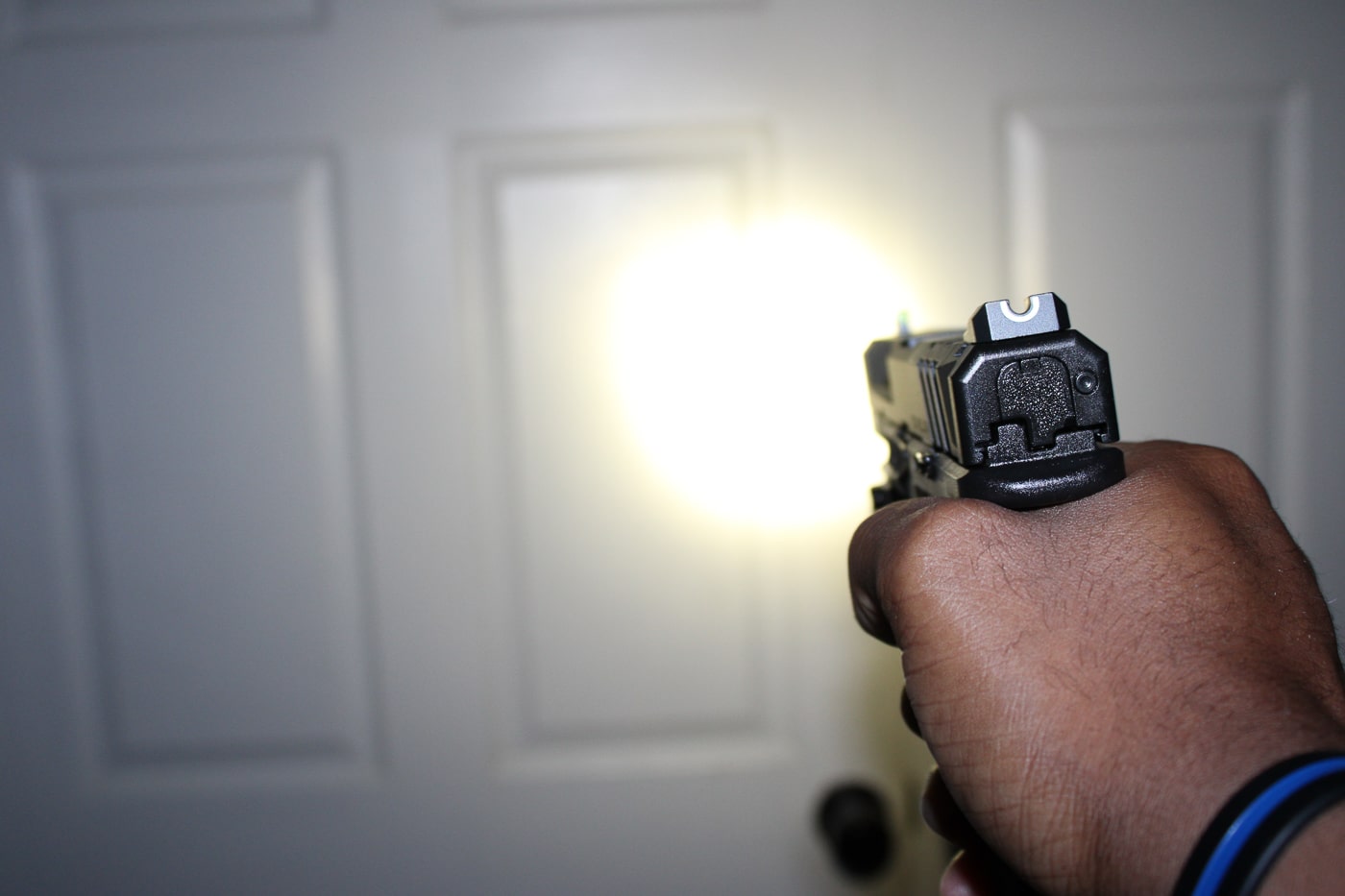 Three-quarter view of a Springfield Armory Echelon full-size pistol with a compact weapon light mounted on the accessory rail, photographed against a neutral surface to emphasize features and form. The optics-ready slide and tall, easily visible iron sights are clearly shown, illustrating options for both red-dot integration and conventional sighting. The mounted light housing and lens face forward; controls such as the slide stop and magazine release are visible but unobtrusive. This image is optimized for content about Springfield Armory bug out guns, full-size defensive pistols, and tactical accessory setups. Textures on the polymer frame and slide serrations are in focus, conveying a durable, service-oriented finish rather than decorative flair. No people are present, and the composition is clearly intended to show gear readiness and accessory compatibility for emergency carry and home defense.
