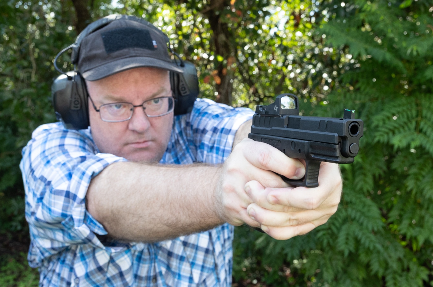 Shooter using optics-equipped Springfield pistol at gun club range demonstrating membership benefits of equipment knowledge and community expertise. Gun clubs connect firearm owners with experienced members who share information about red dot sights modifications and shooting techniques. Joining shooting clubs provides access to shooters with practical knowledge about handgun optics pistol accessories and gear choices. Firearms club membership offers community connections where members discuss equipment like optic slides reflex sights and pistol modifications. Shooting range club members learn from experienced gun owners about firearm accessories optics systems and modification options through informal knowledge sharing and hands-on demonstrations.